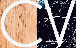 A split image with a wood texture background on the left and a black marble texture on the right, featuring large white overlapping letters 'C' and 'V'.