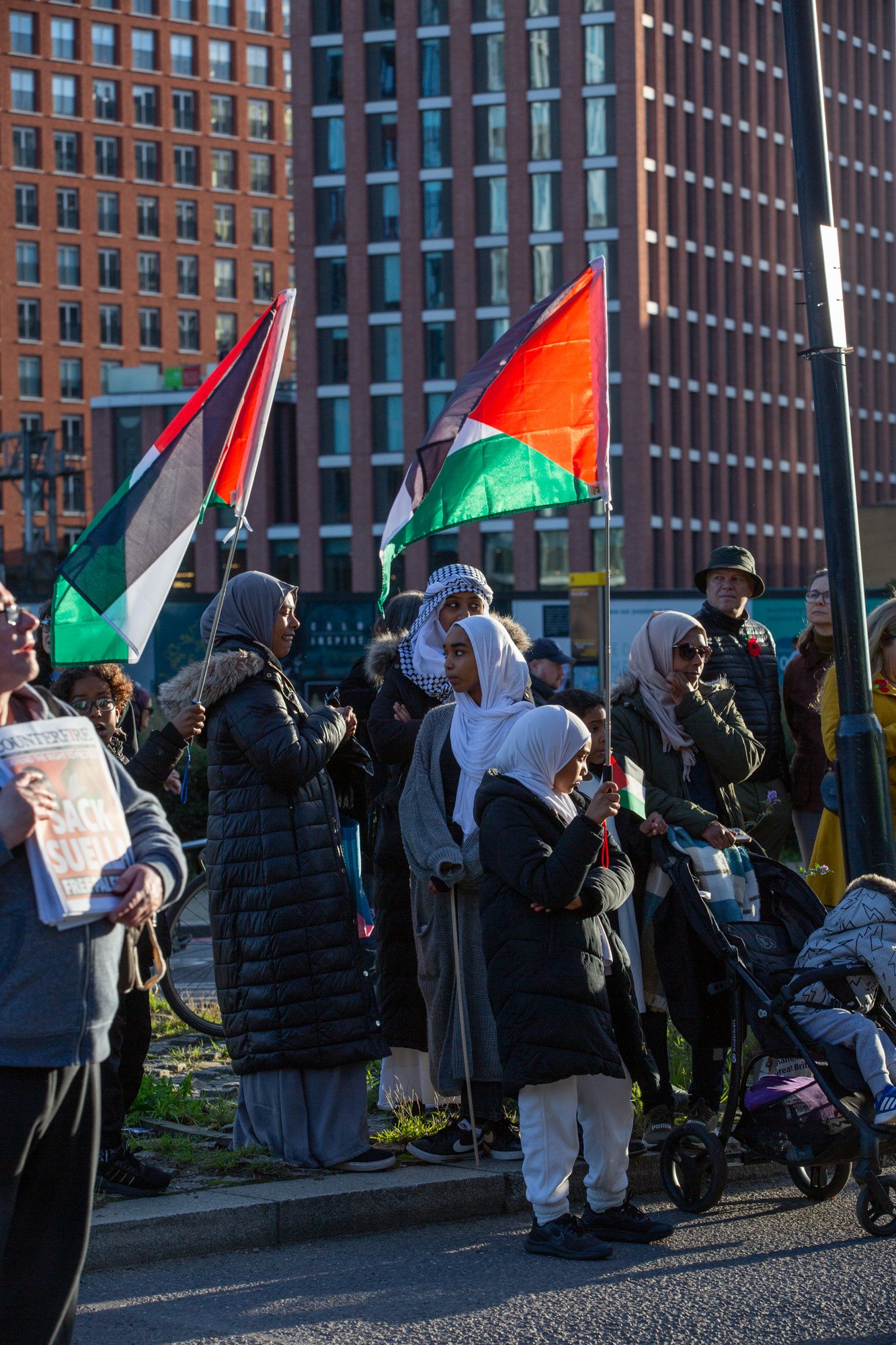 A group of women hold Palestine flags as they watch protesters march through London - November 12, 2023