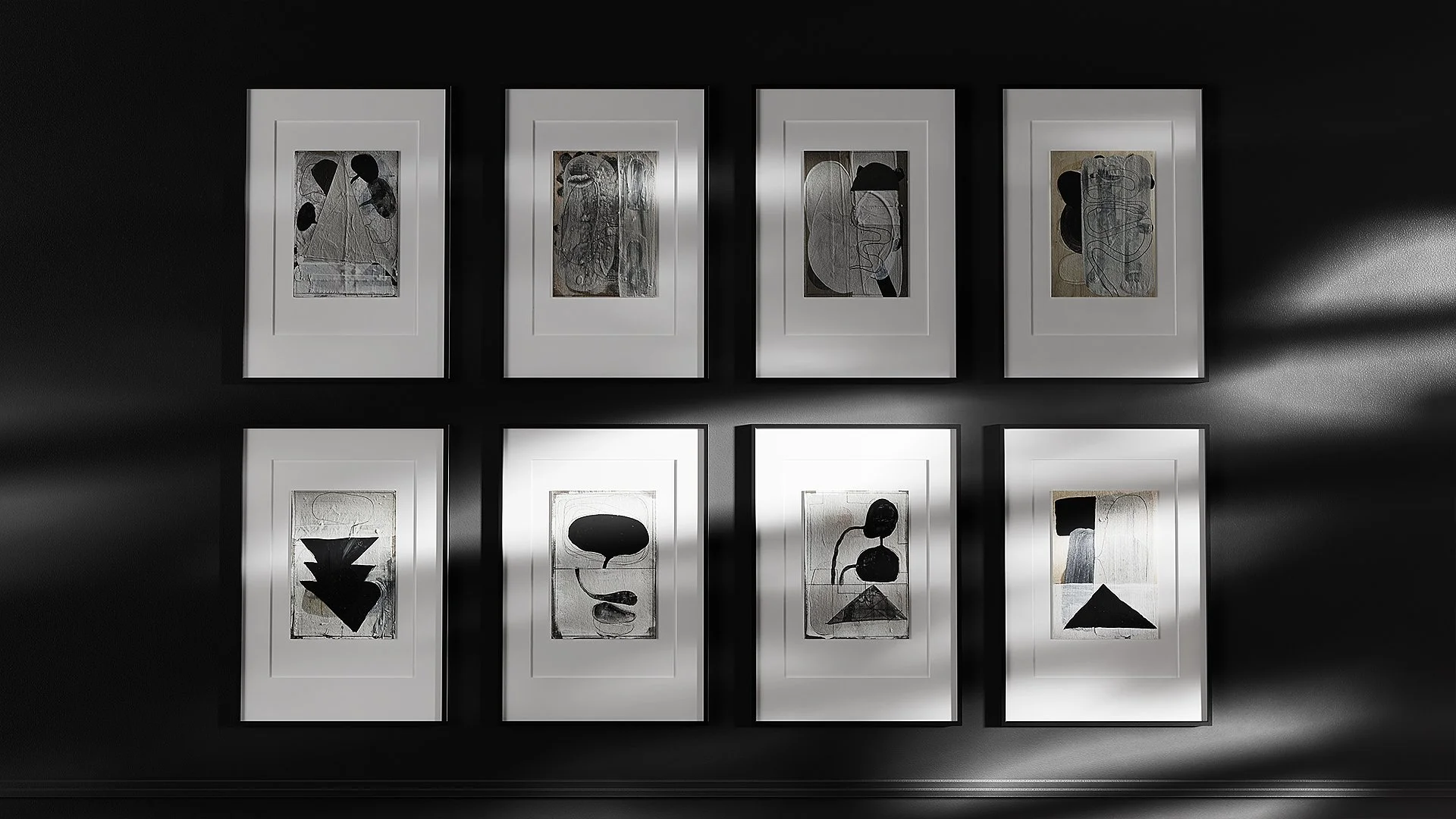 A wall display with eight framed abstract black and white artworks arranged in two rows of four, with dramatic light casting shadows across them.