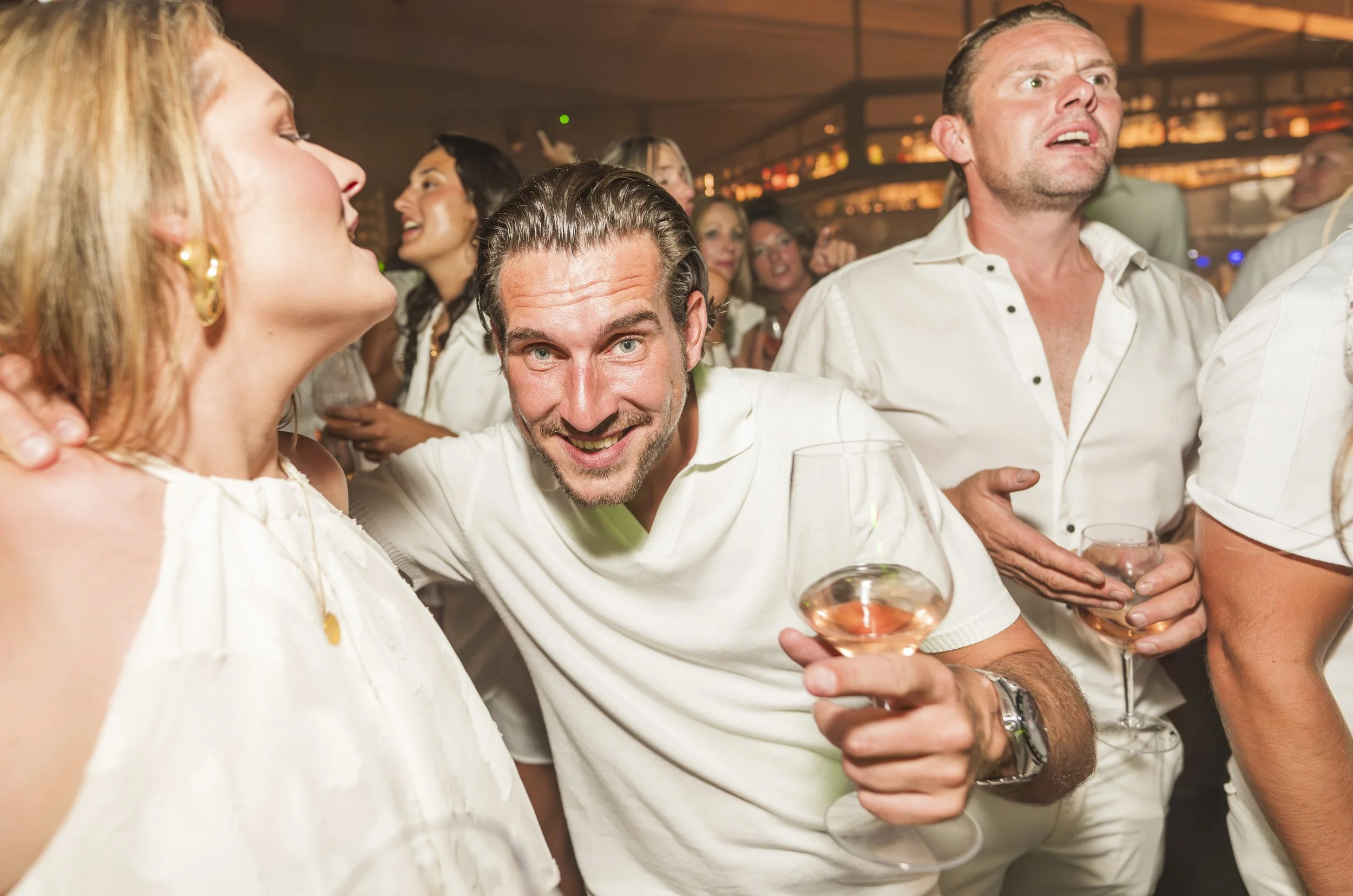 Mensen die samen genieten van een feest in een bar, met enkele mensen die wijn drinken en lachen.