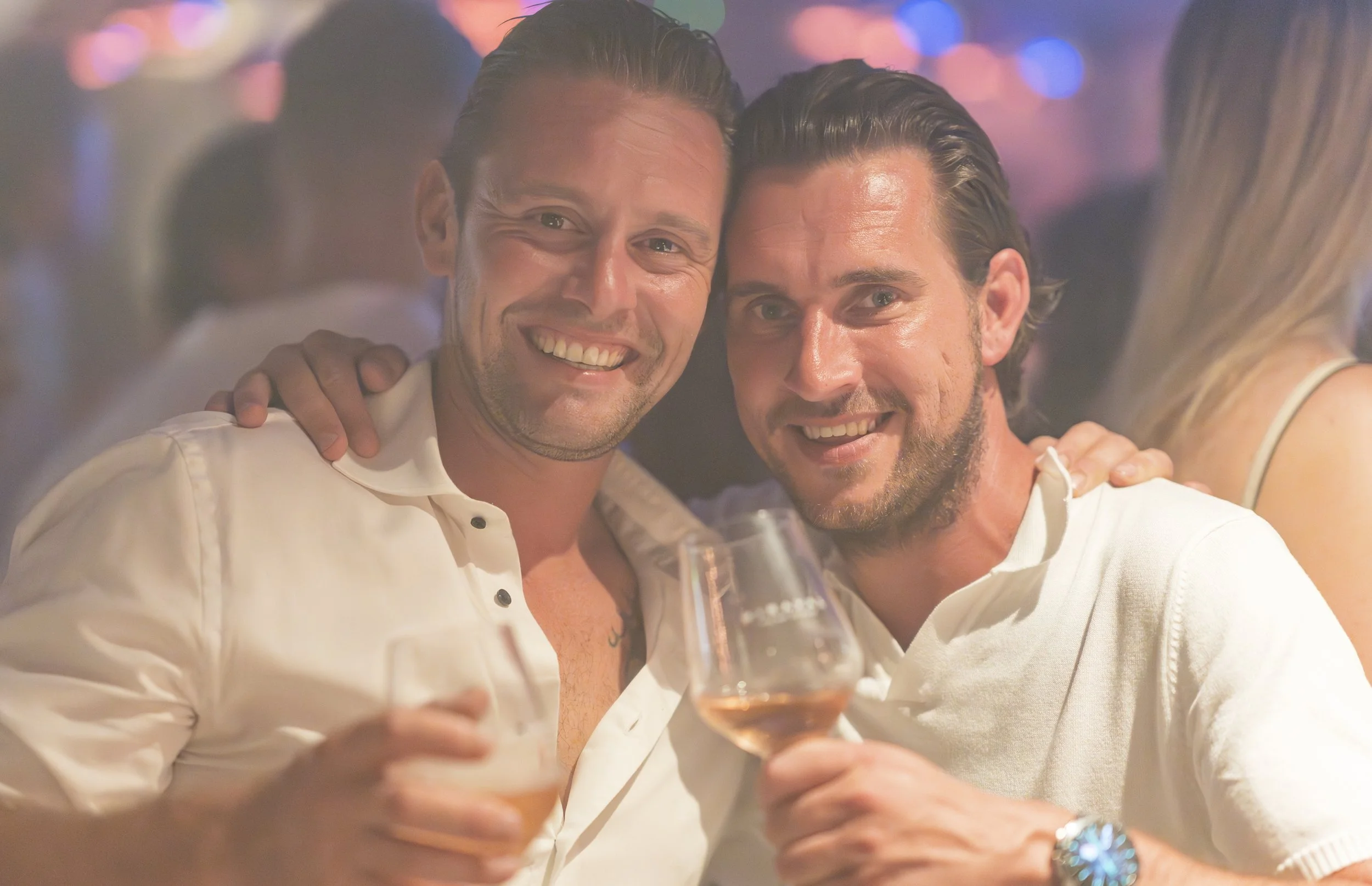 Twee mannen lachen en toasten met glazen champagne in een feestelijke setting.