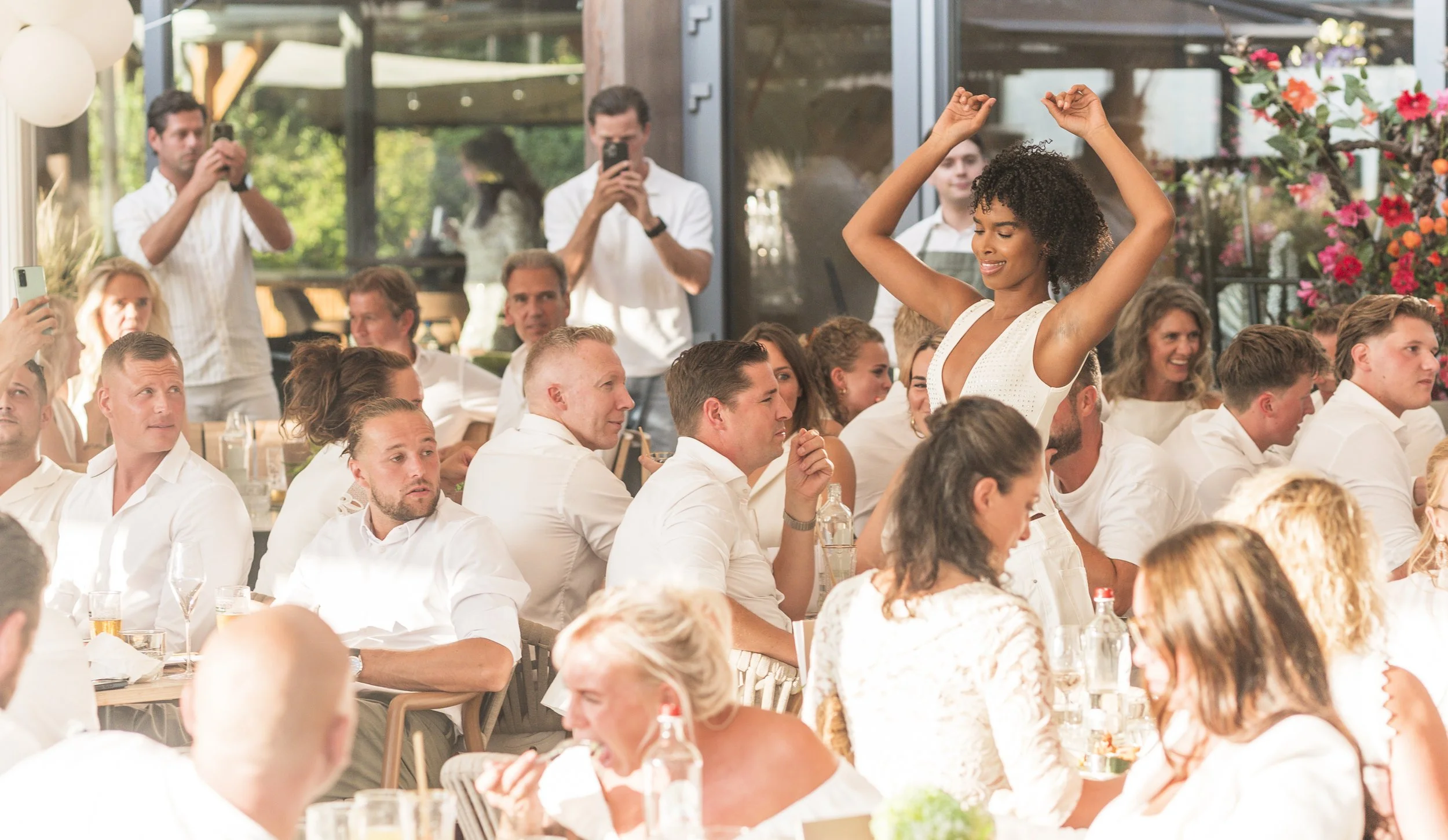 Feestvierende mensen op een feest, met een vrouw die dansen en lachen in het midden.