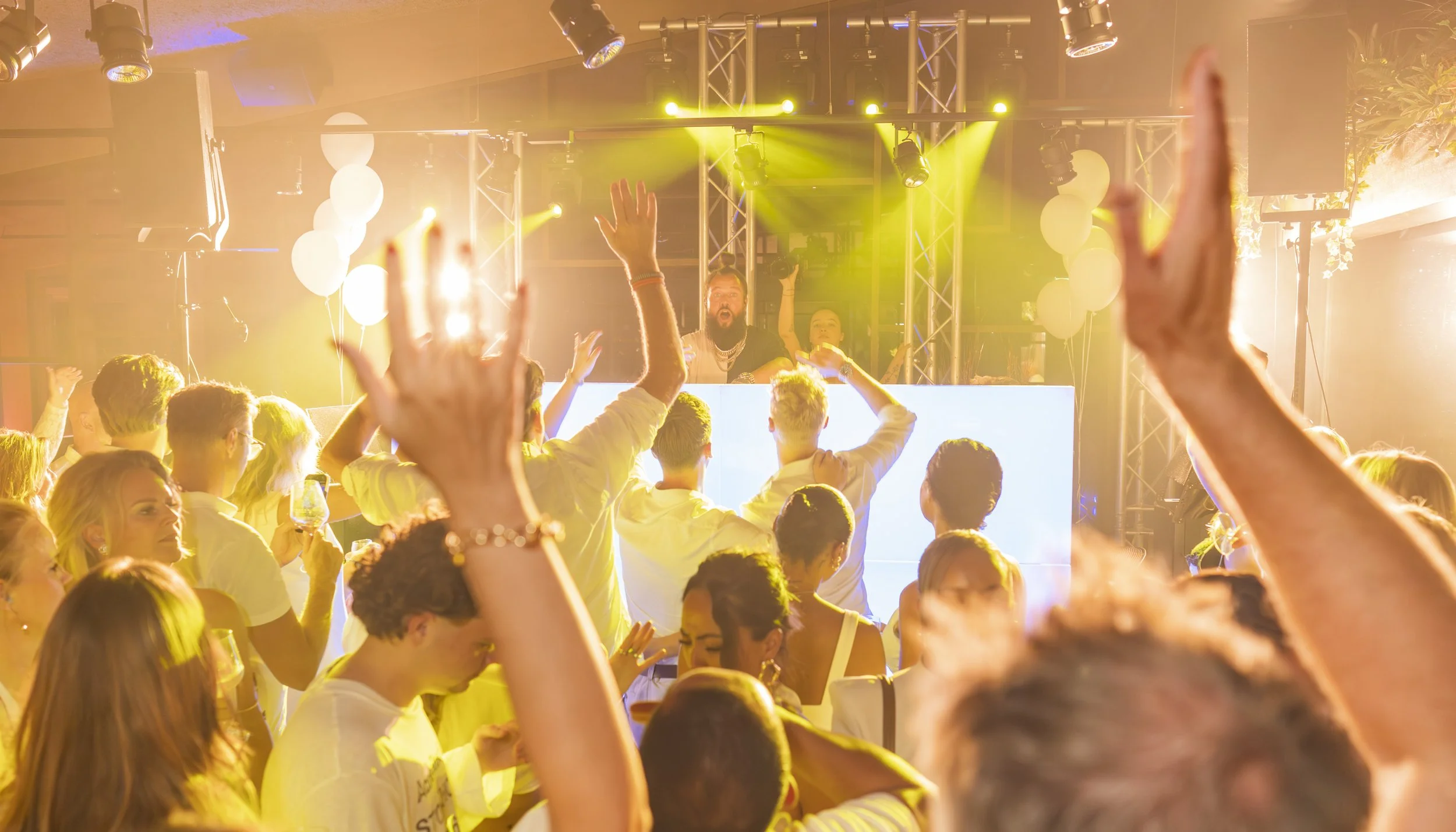 Een dansfeest met mensen die plezier maken onder gele en witte lichten, ingrediënten voor een feeststemning.