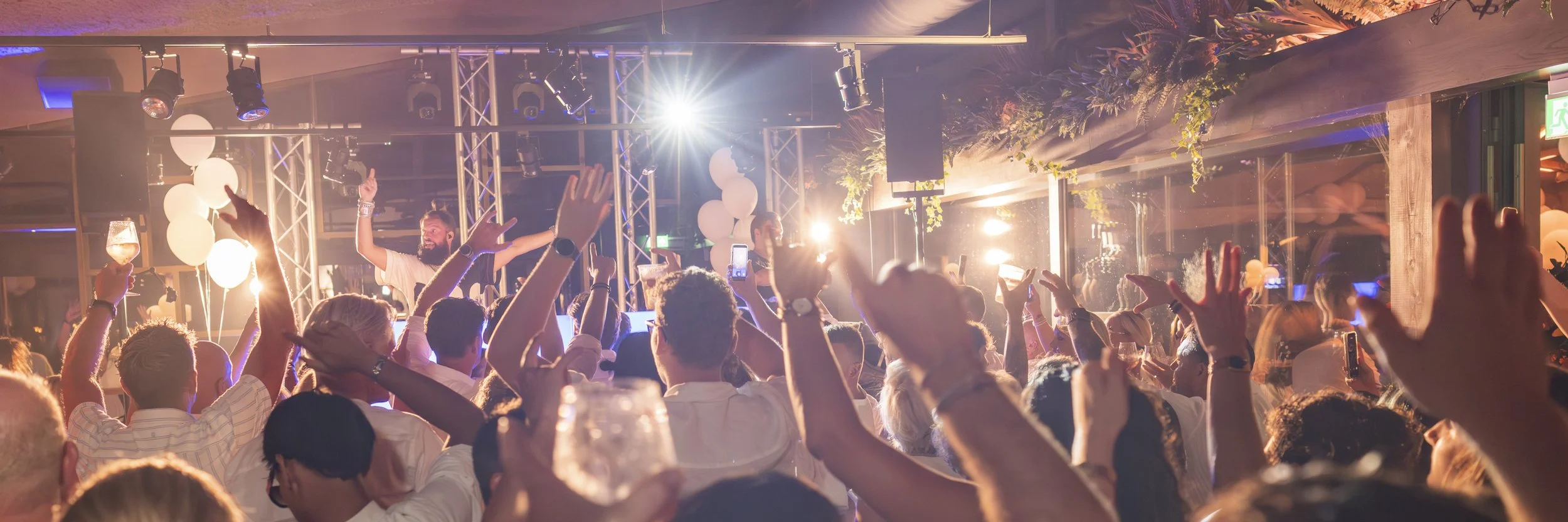 Mensen dansen en genieten van een concert of dj optreden op een feest met kleurrijke verlichting en decoraties.
