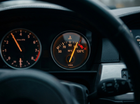 European vehicle temperature gauge showing engine running above normal operating range, needle climbing toward the red zone warning indicator