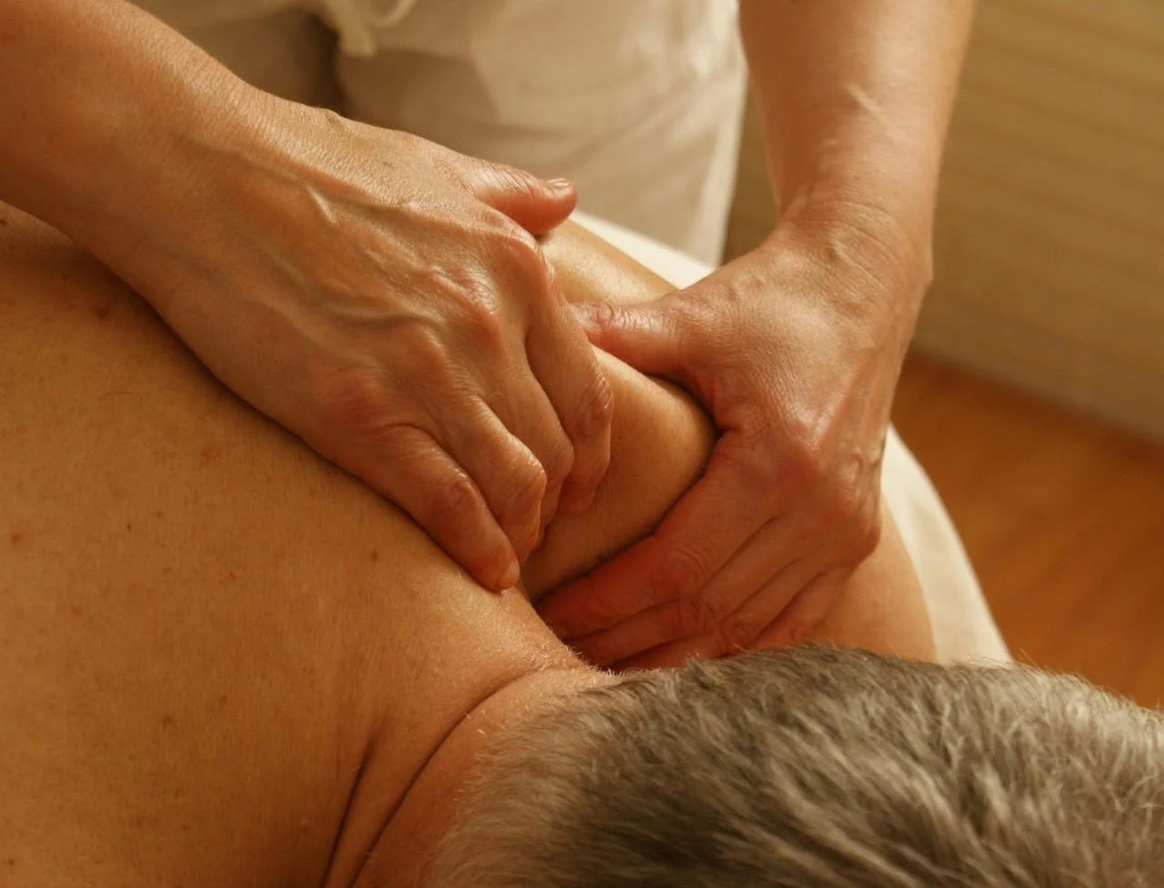 Close-up of a person receiving a massage on their back, with a massage therapist's hands applying pressure.