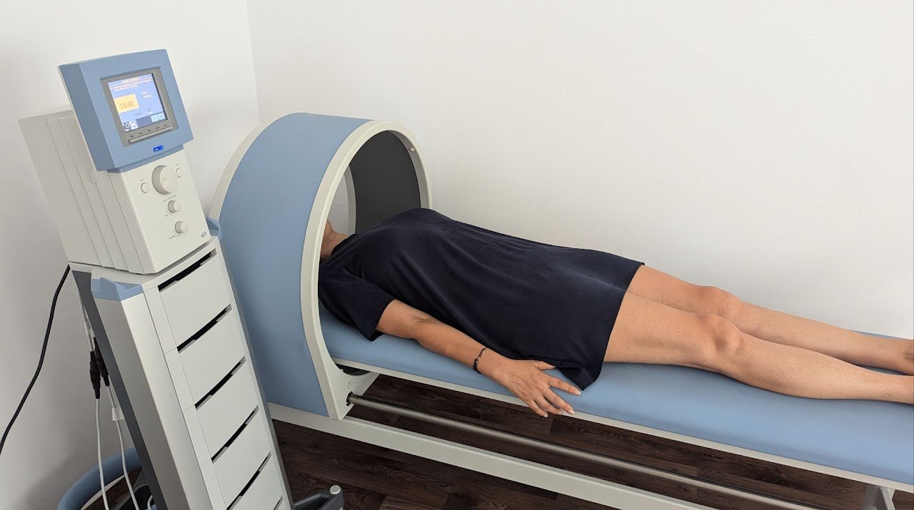 A person lying face down on a medical imaging table, preparing for a scan, with a large circular machine around their head.