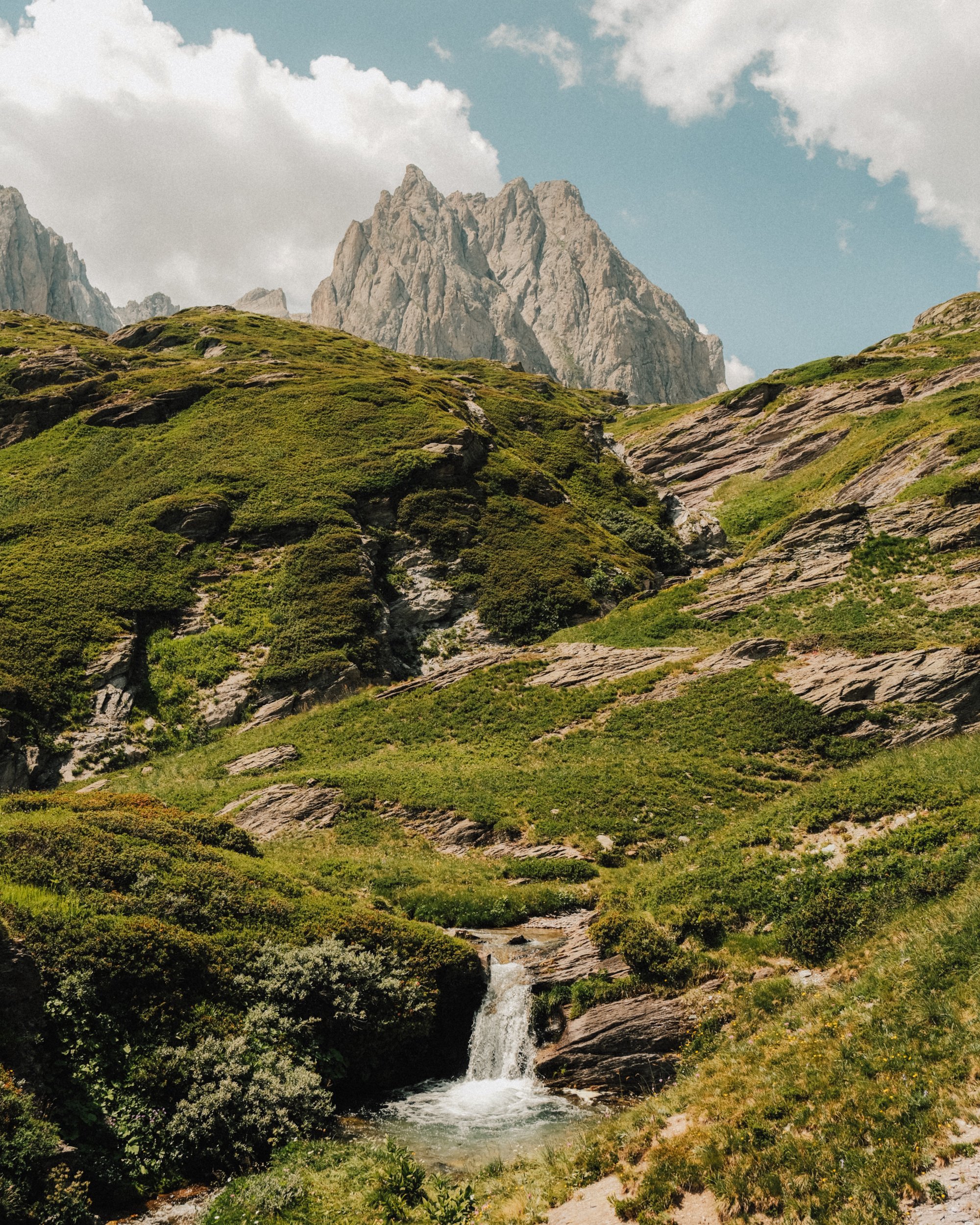 Paysage de montagne avec sommet rocheux, vallées verdoyantes, petit torrent et ciel nuageux. Paysages, photo, montagne, rando, randonnée, sport, outdoor, exposition, massif des cerces