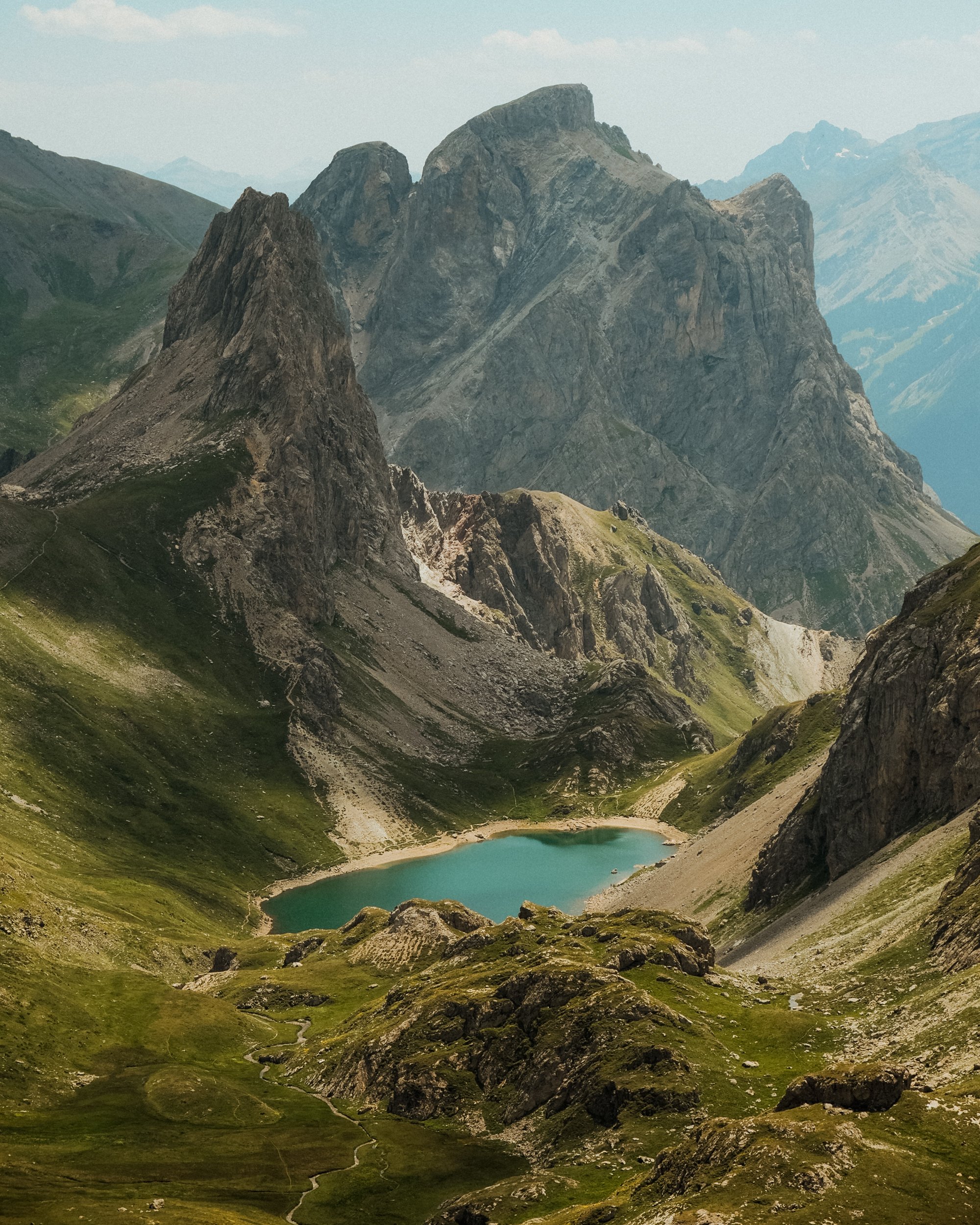 Paysage de montagnes avec un lac turquoise au centre, entouré de sommets rocheux et verts, dans une vallée alpine. Paysages, photo, montagne, rando, randonnée, sport, outdoor, exposition. massif des cerces