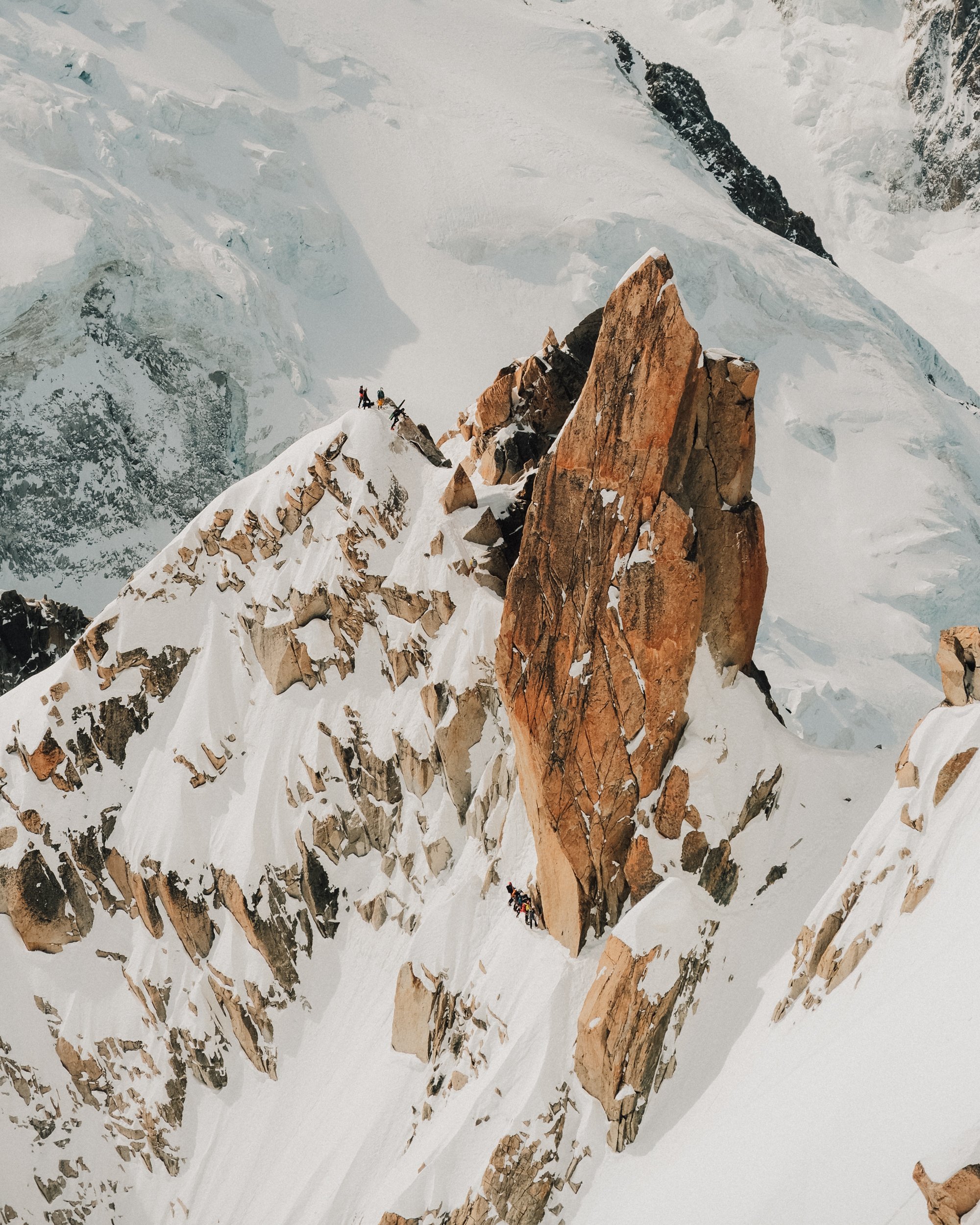 Ascension d'une cordée d'alpinistes sur une crête enneigée entre de grandes formations rocheuses dans un environnement glaciaire. Paysages, photo, montagne, rando, randonnée, sport, outdoor, exposition