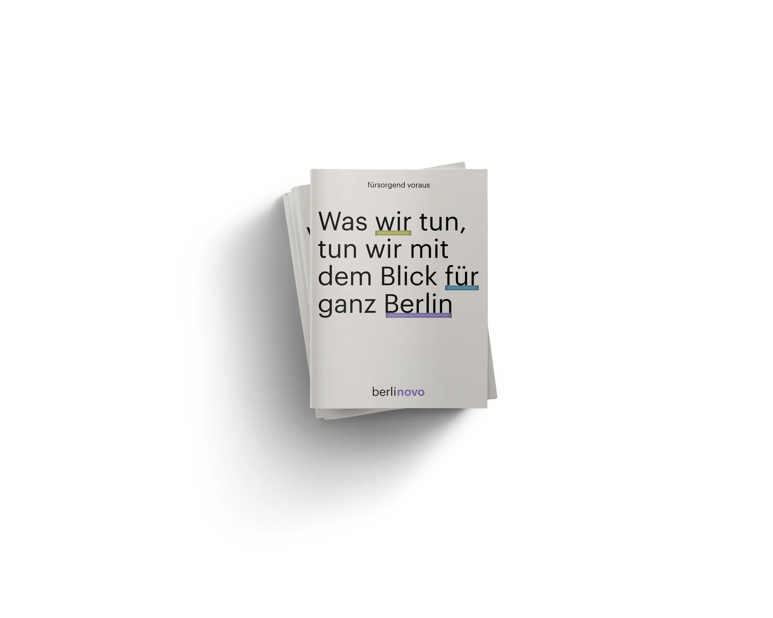 A white booklet with black, purple, blue, and yellow highlighted text, titled 'Was wir tun, tun wir mit dem Blick für ganz Berlin,' placed on a white surface with a soft shadow.