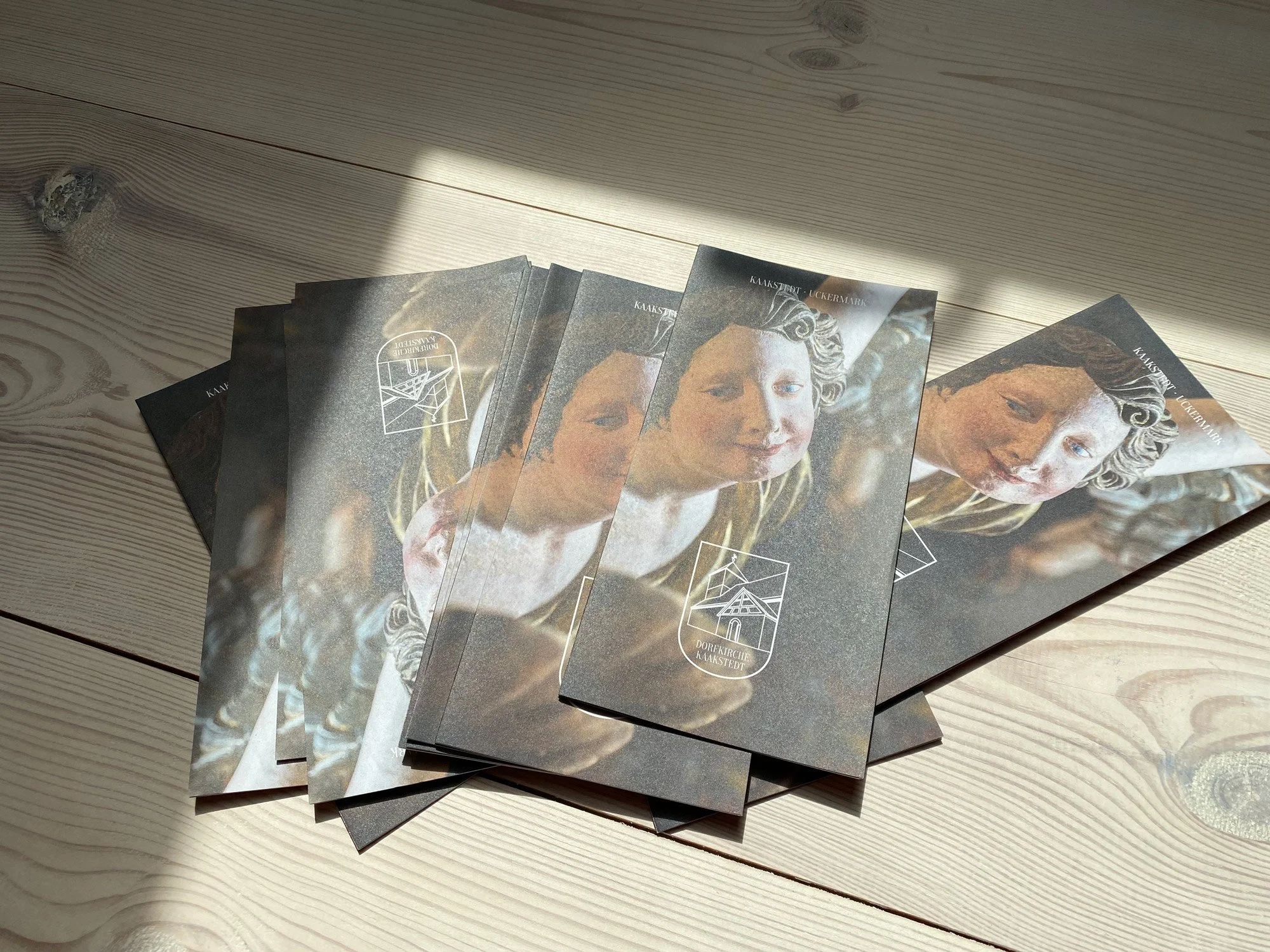 Several brochures or flyers with an image of a smiling woman with curly hair on a wooden surface, some partially overlapping each other.