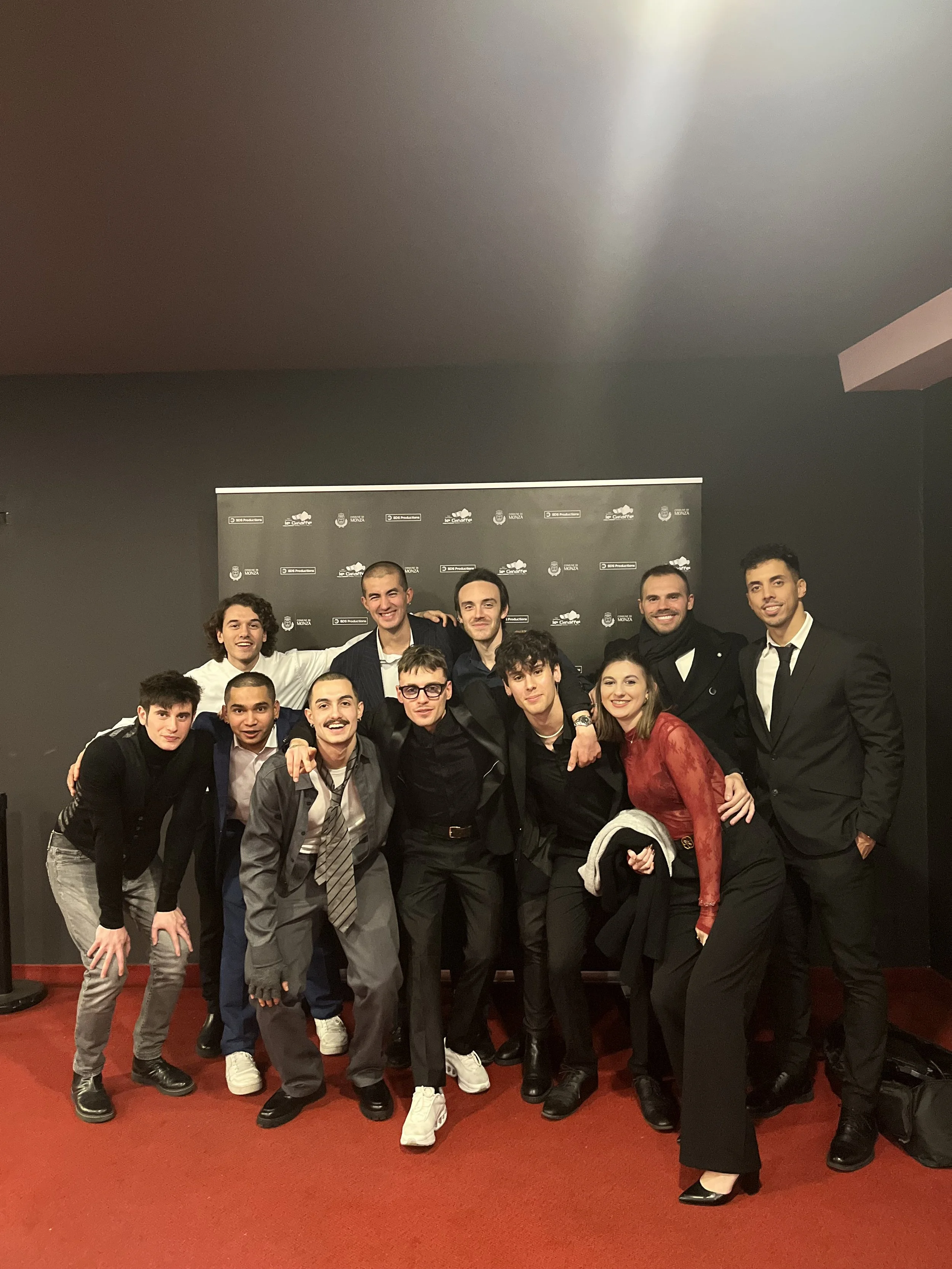 Gruppo di persone sorridenti e ben vestite che posano insieme, probabilmente alla fine di un evento o di uno spettacolo.