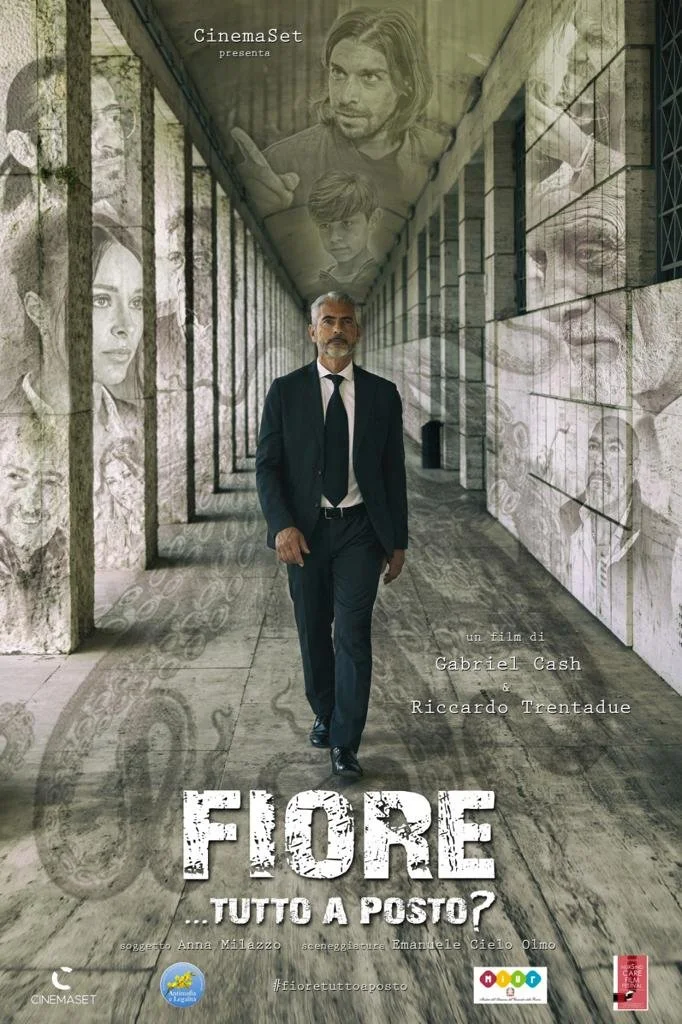 Locandina del film 'Fiore... tutto a posto?' con un uomo vestito in giacca e cravatta che cammina lungo un corridoio decorato con immagini di persone e ricordi.
