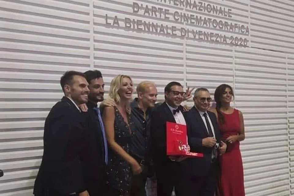 Gruppo di persone sorridenti in occasione della cerimonia della 77ª Mostra Internazionale d'Arte Cinematografica di Venezia nel 2020.