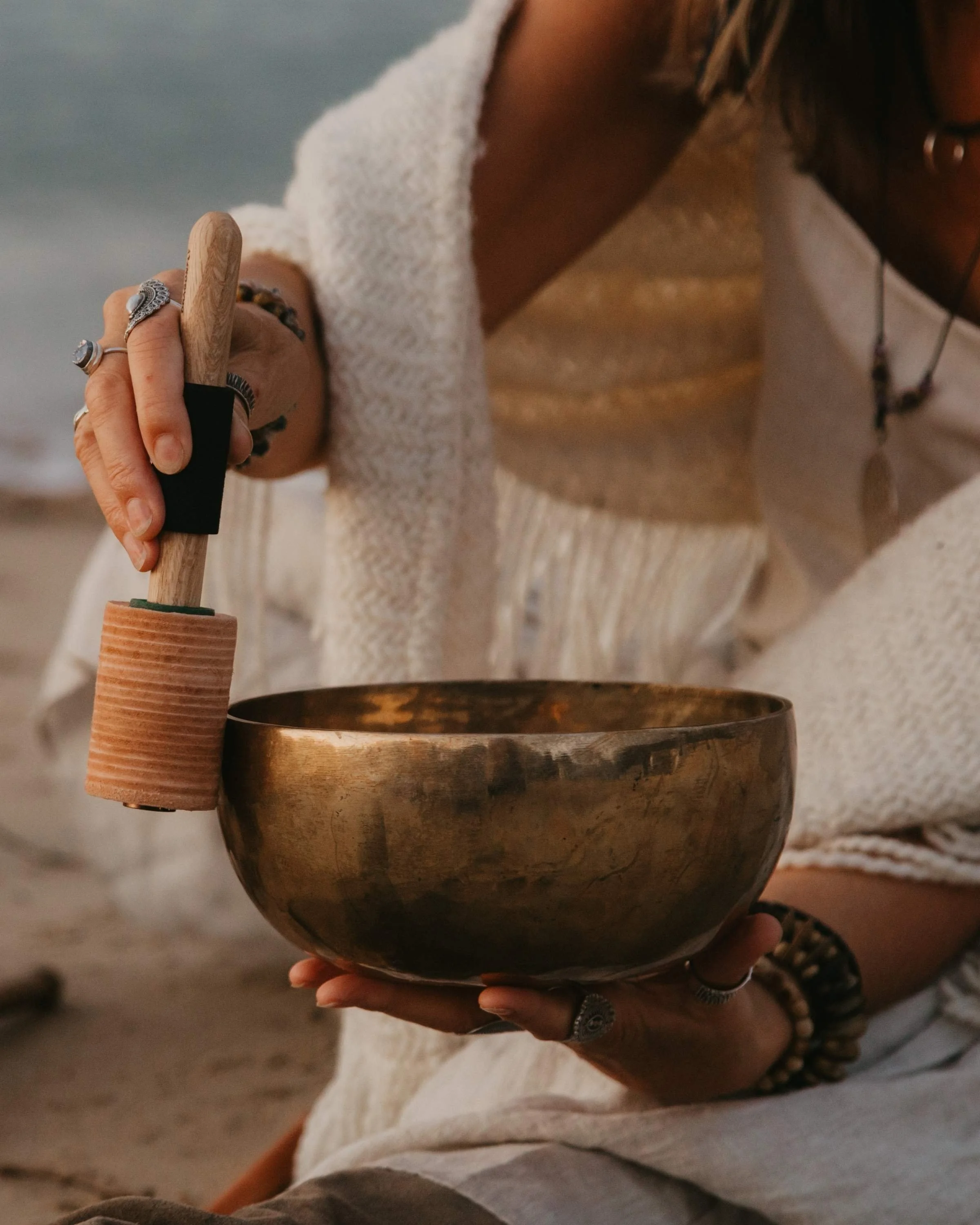 Close up of Alison Palmer, Sound practitioner trainer demonstrating how to wind a himalayan singing bowl by rubbing a mallet around the rim