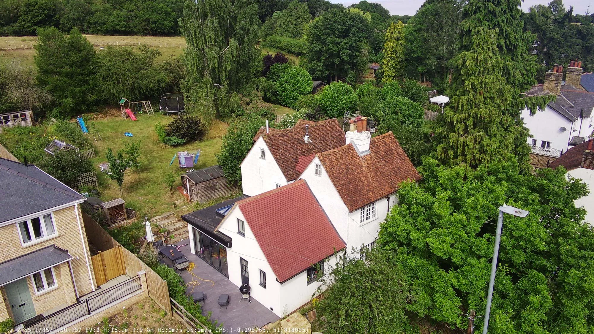 Birds-eye view of a rural English hamlet featuring multiple red-roof homes nestled among greenery.