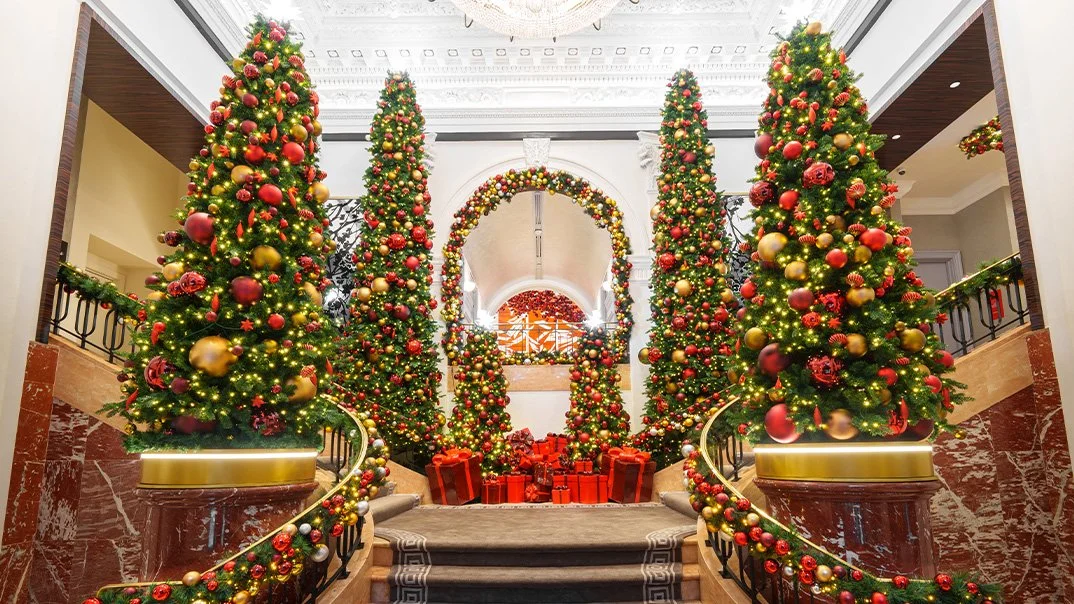 Large hotel lobby and stair case with red and yellow decorations on large christmas trees