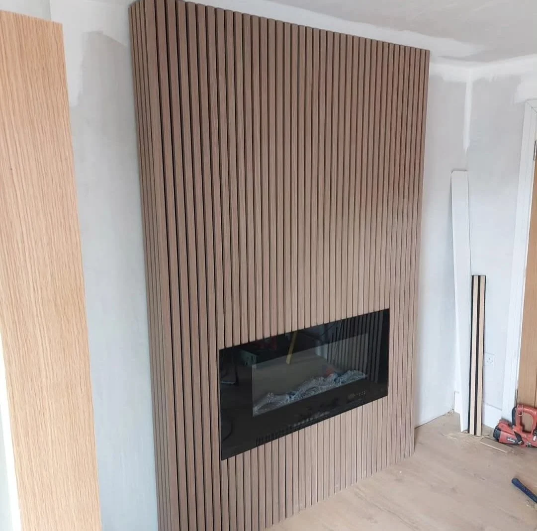 Wood-paneled fireplace wall in a room under construction.