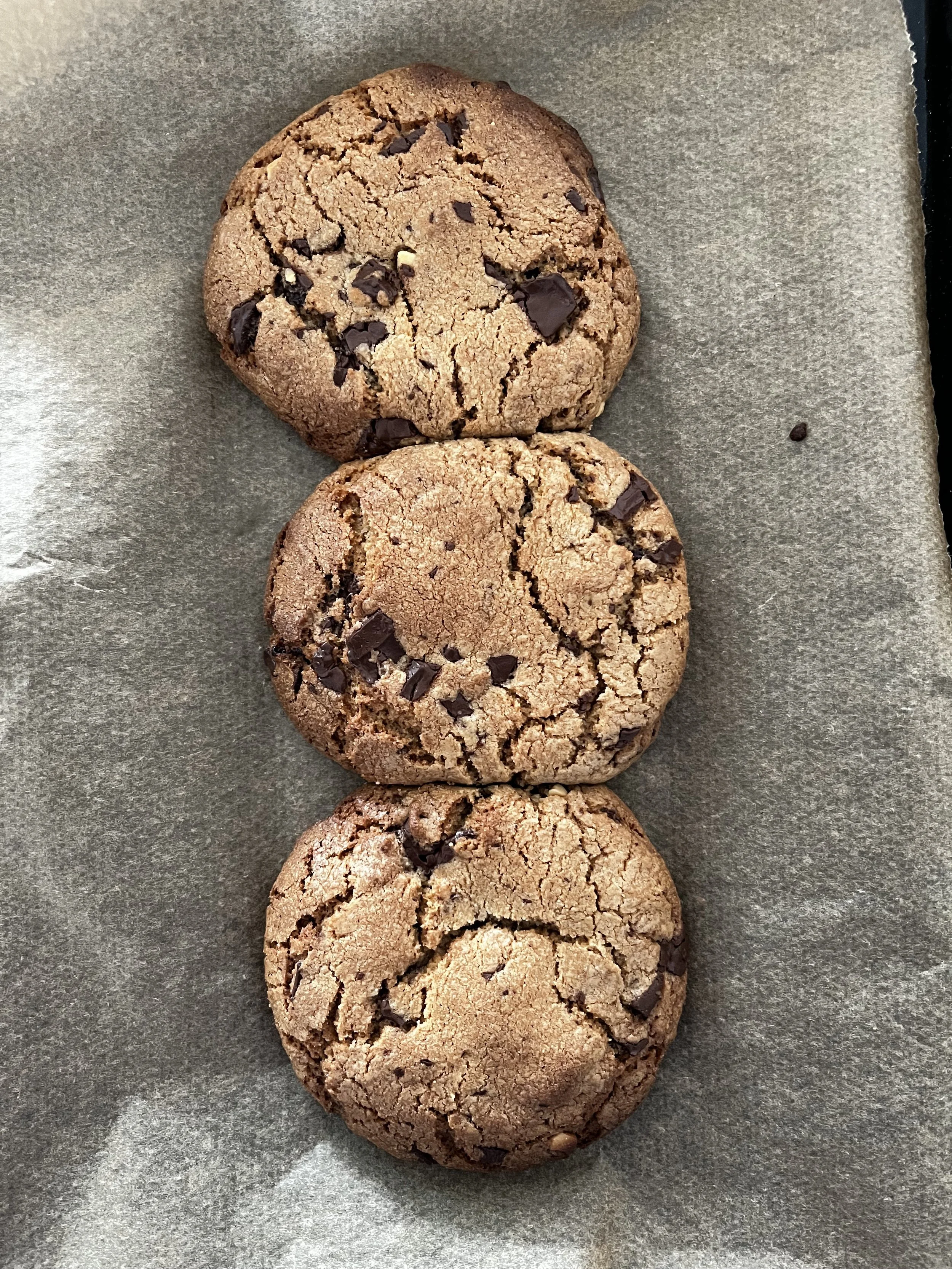 Three chocolate chip cookies on parchment paper