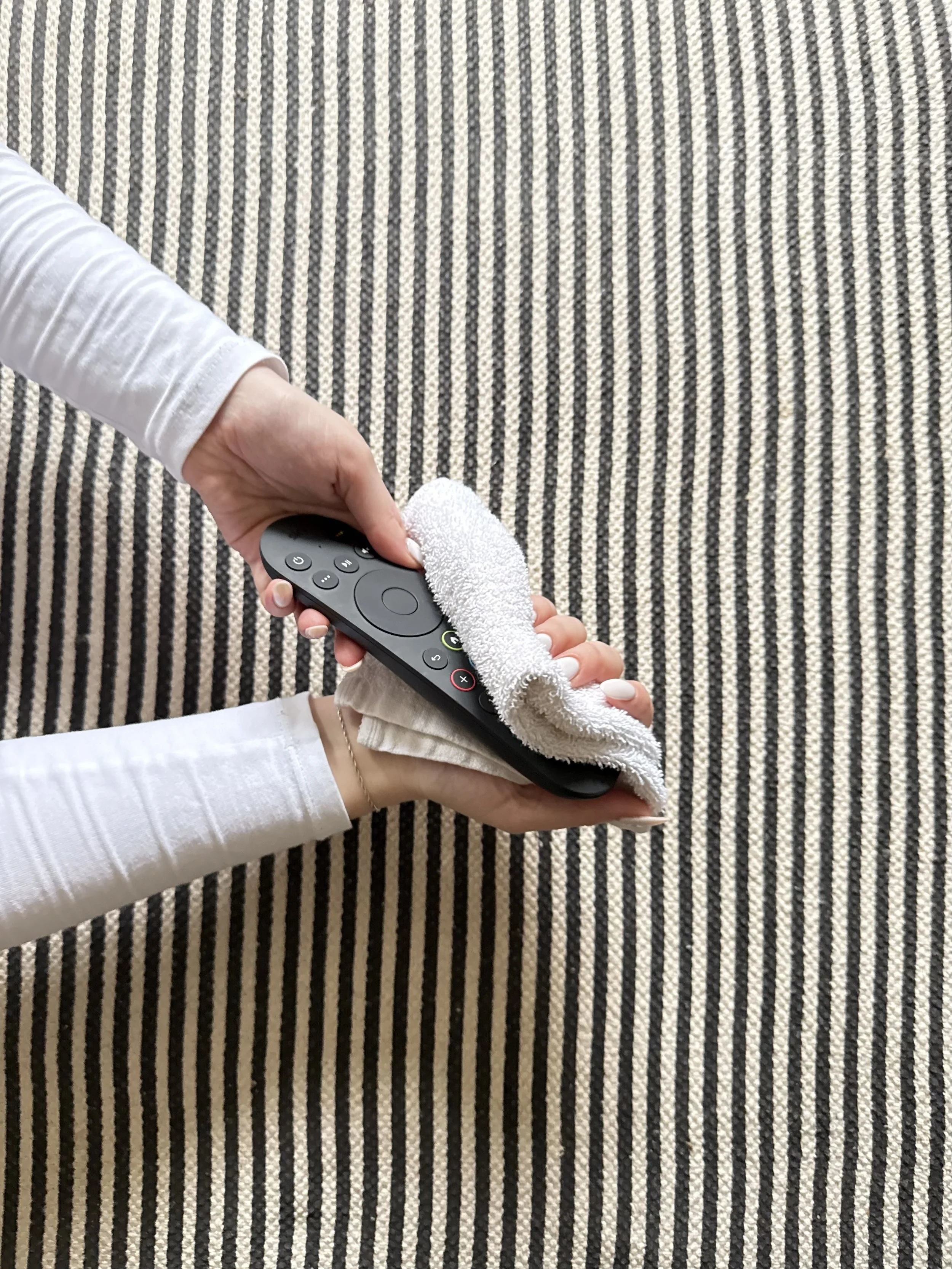 Person cleaning a TV remote control with a white cloth.