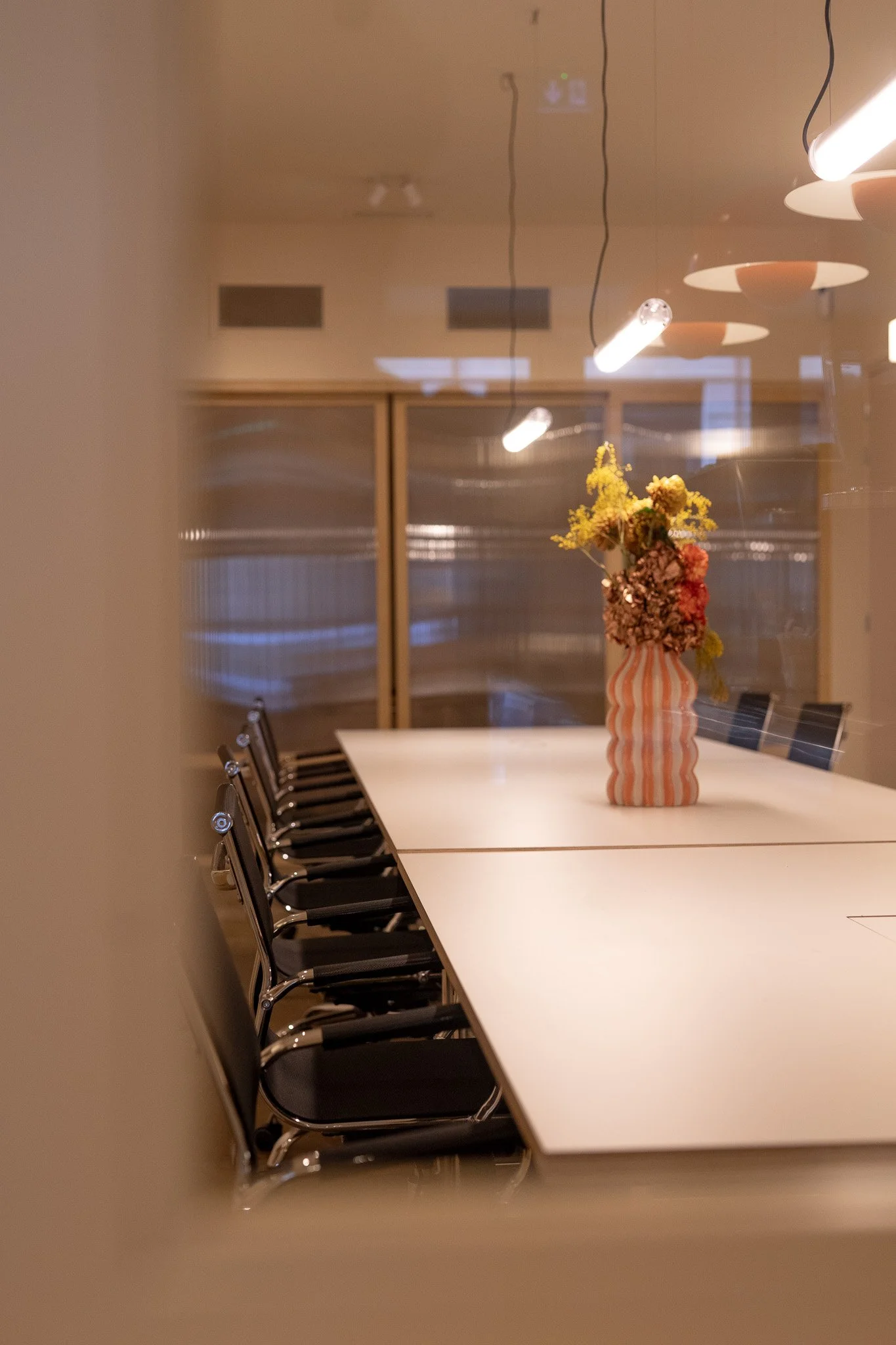 Openspac, décoration florale dans un vase orange et blanc, éclairage suspendu dans une salle de conférence moderne.