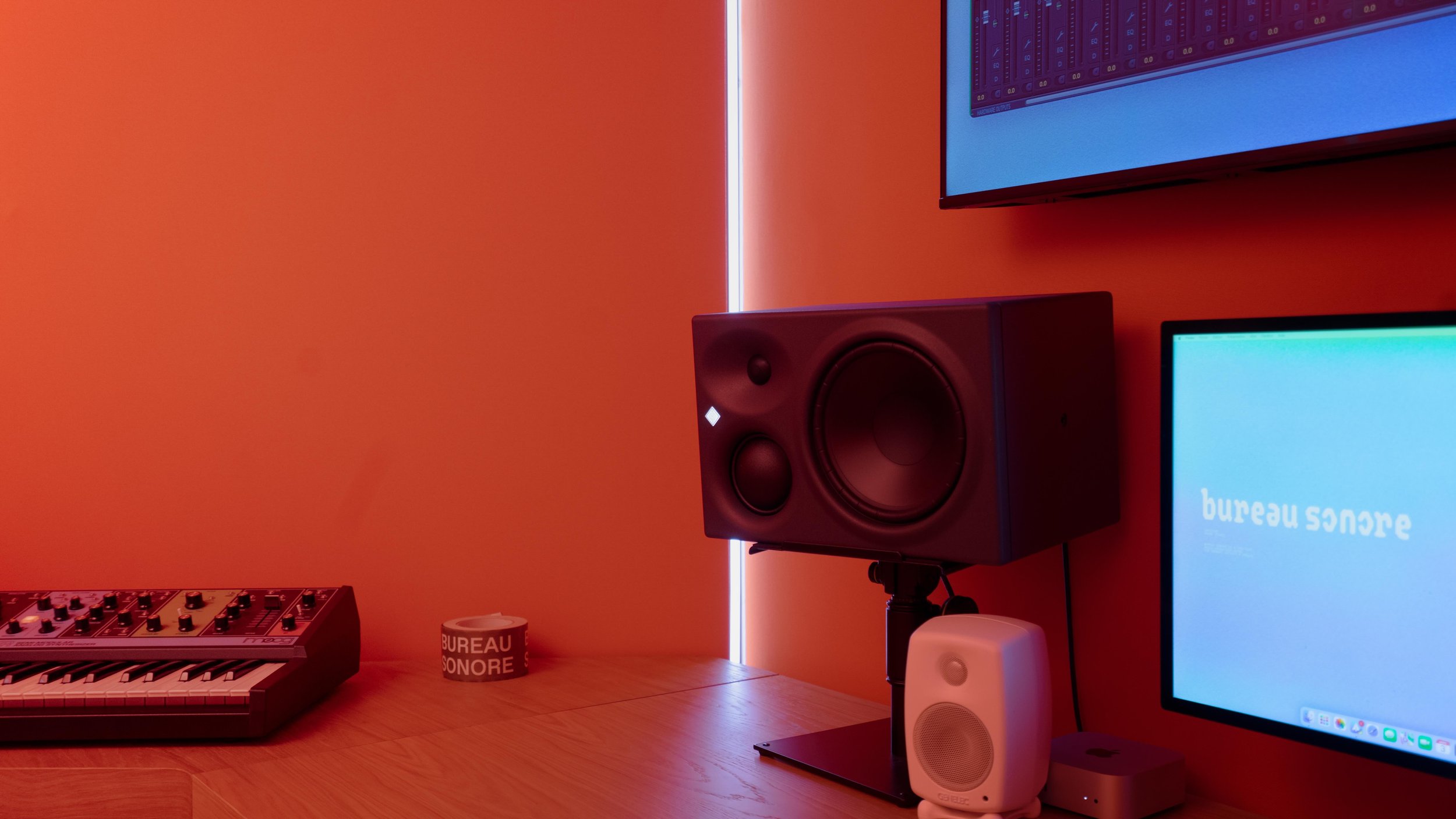 Espace de studio avec un clavier de synthétiseur, haut-parleurs, écran d'ordinateur affichant 'bureau sonore'