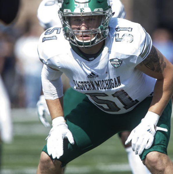 American football player in a white Eastern Michigan jersey with number 51 and a green helmet, in a crouching position on the field.