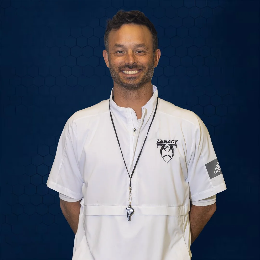 Man standing in front of a backdrop with hands behind back.