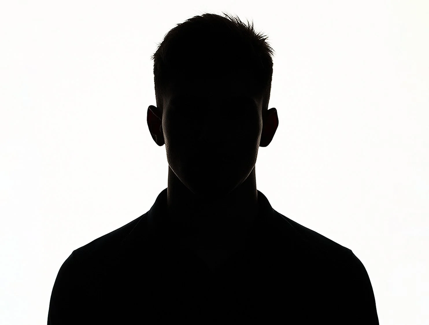Silhouette of a person with short hair, facing forward, against a bright background.