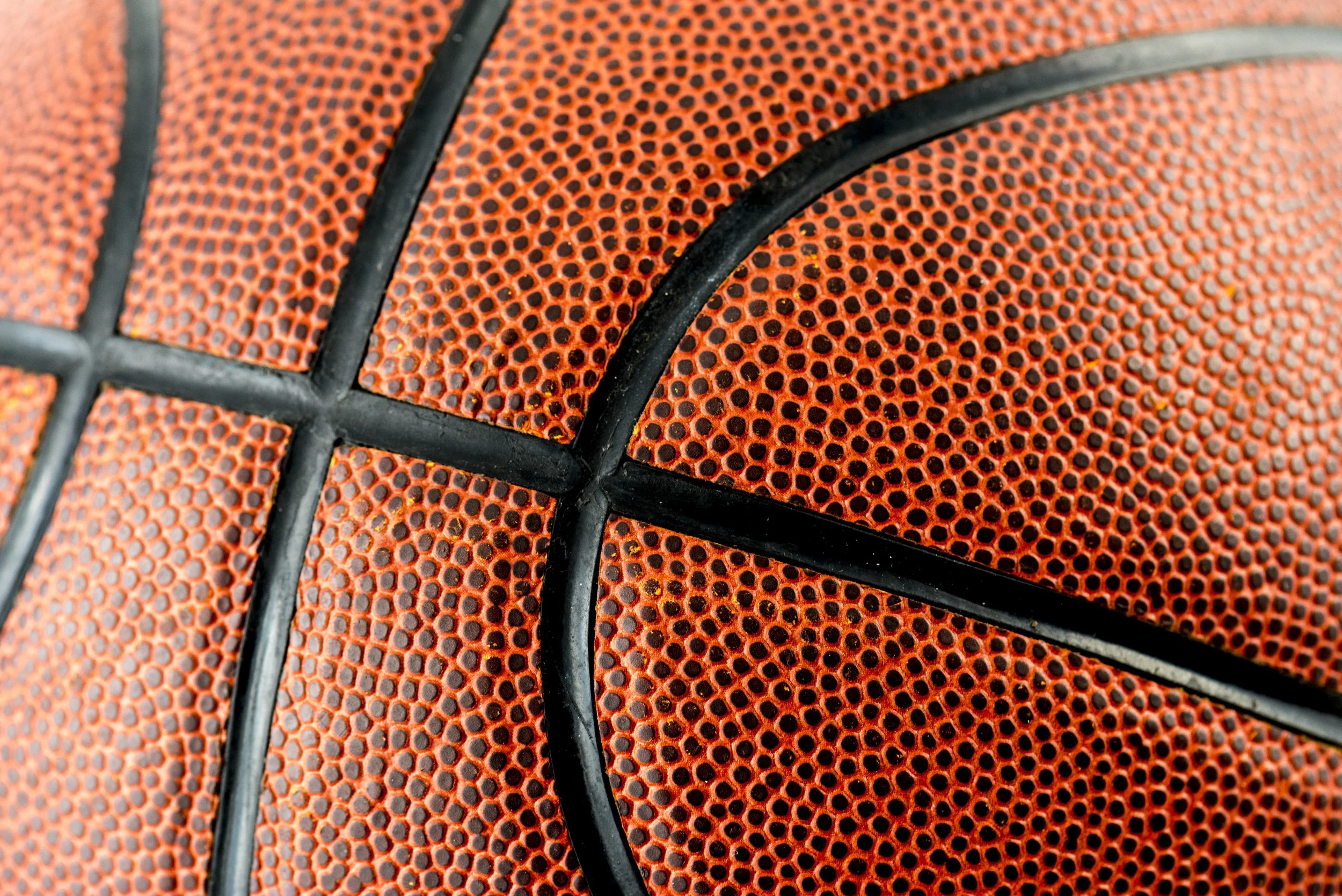 Close-up of a basketball showing textured orange surface with black lines.