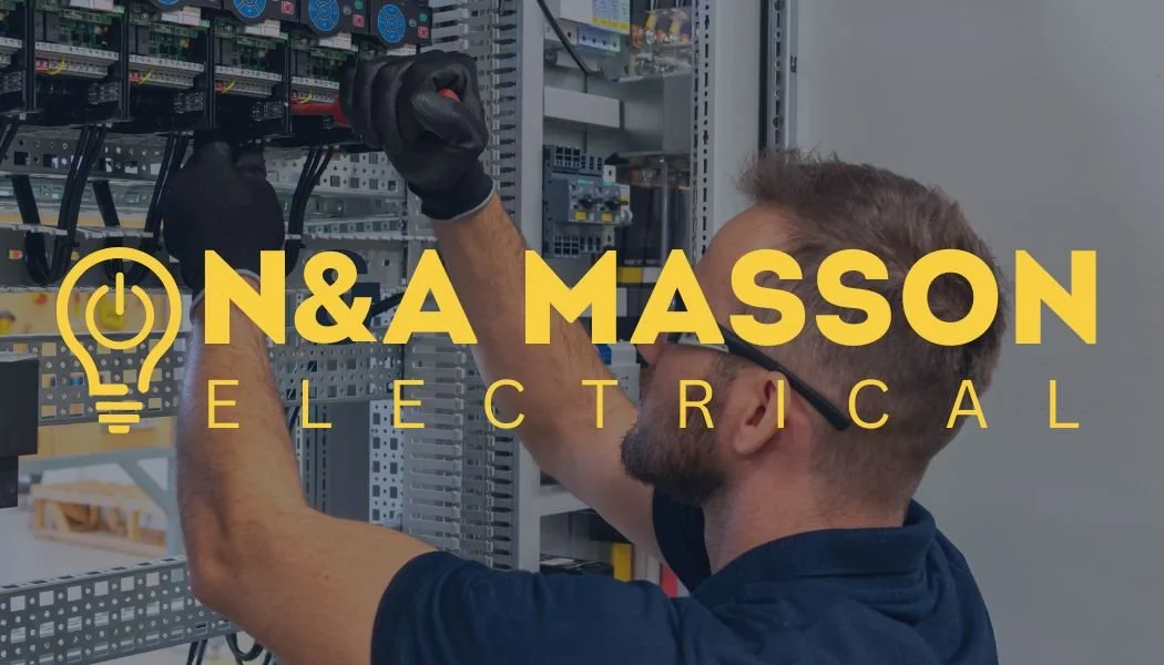 A man with glasses and a beard, wearing a dark blue shirt, working on electrical components inside a control panel or electrical cabinet.