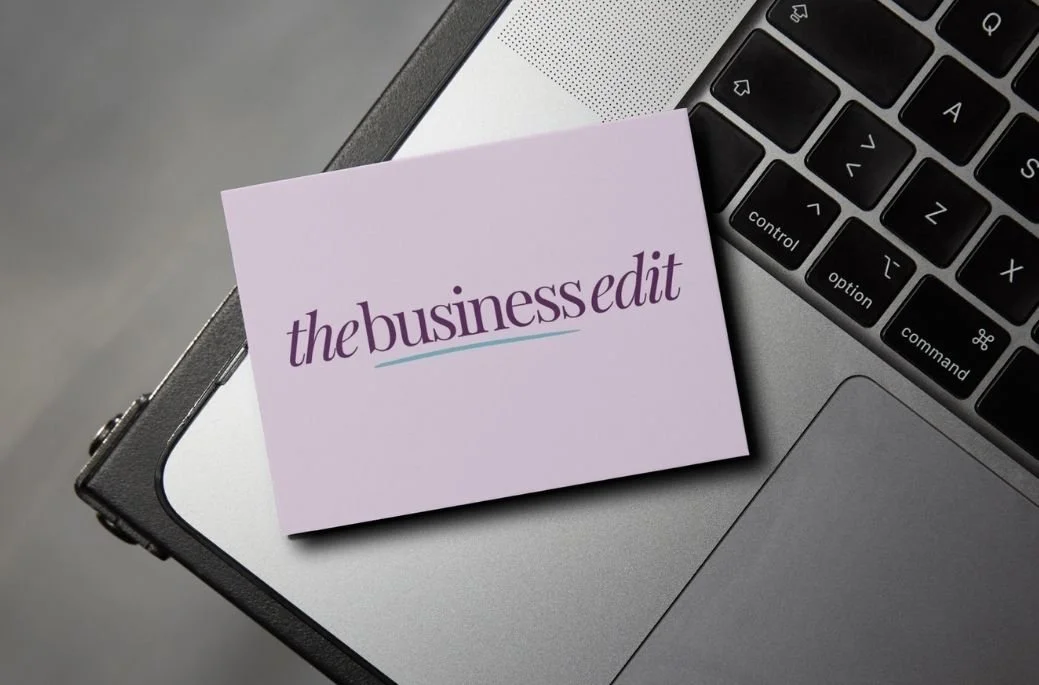 A business card with the logo 'the businesedit' resting on a silver laptop.