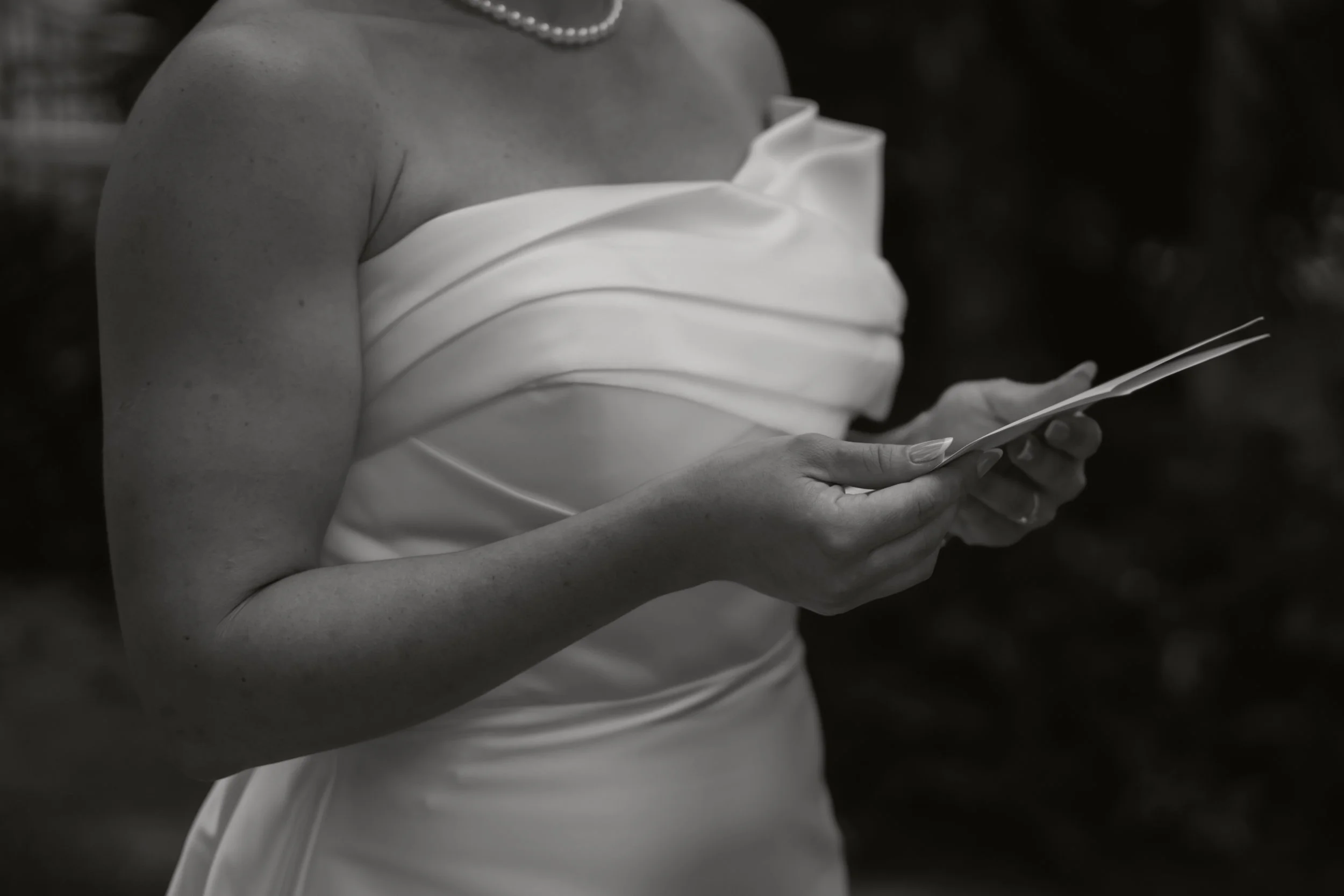 Frau in weißem Kleid liest eine Karte, Nahaufnahme, Schwarz-Weiß