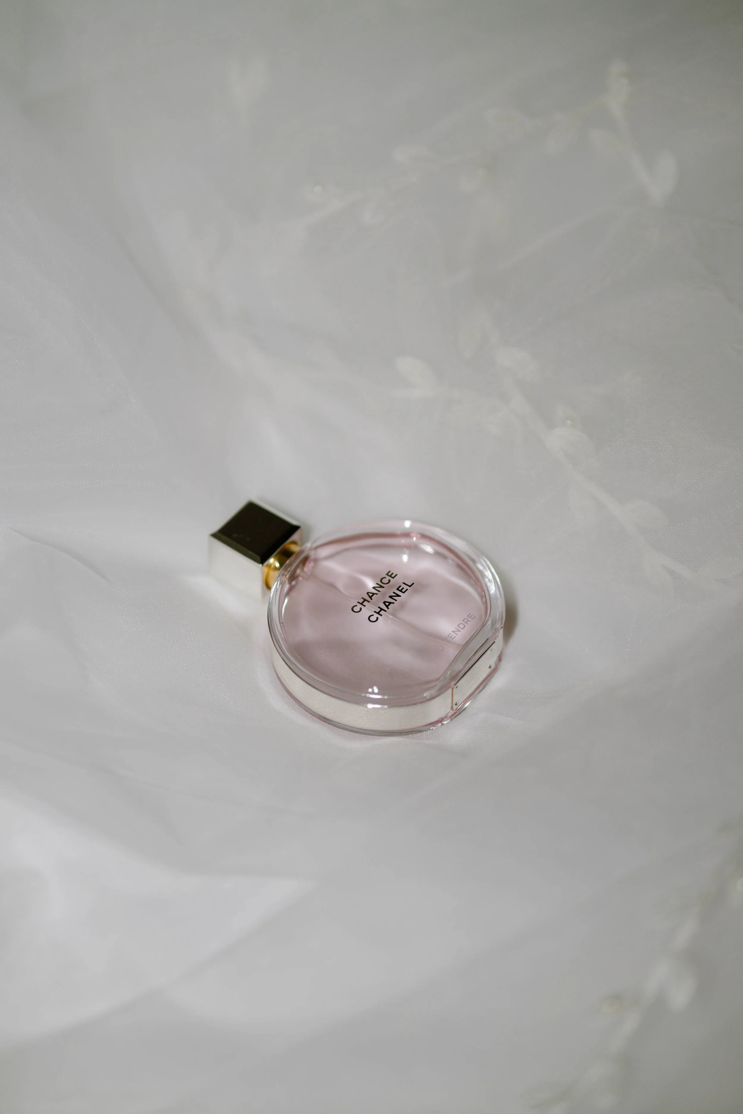 Rosenwasser Parfümflasche von Chanel auf weißem Stoff.