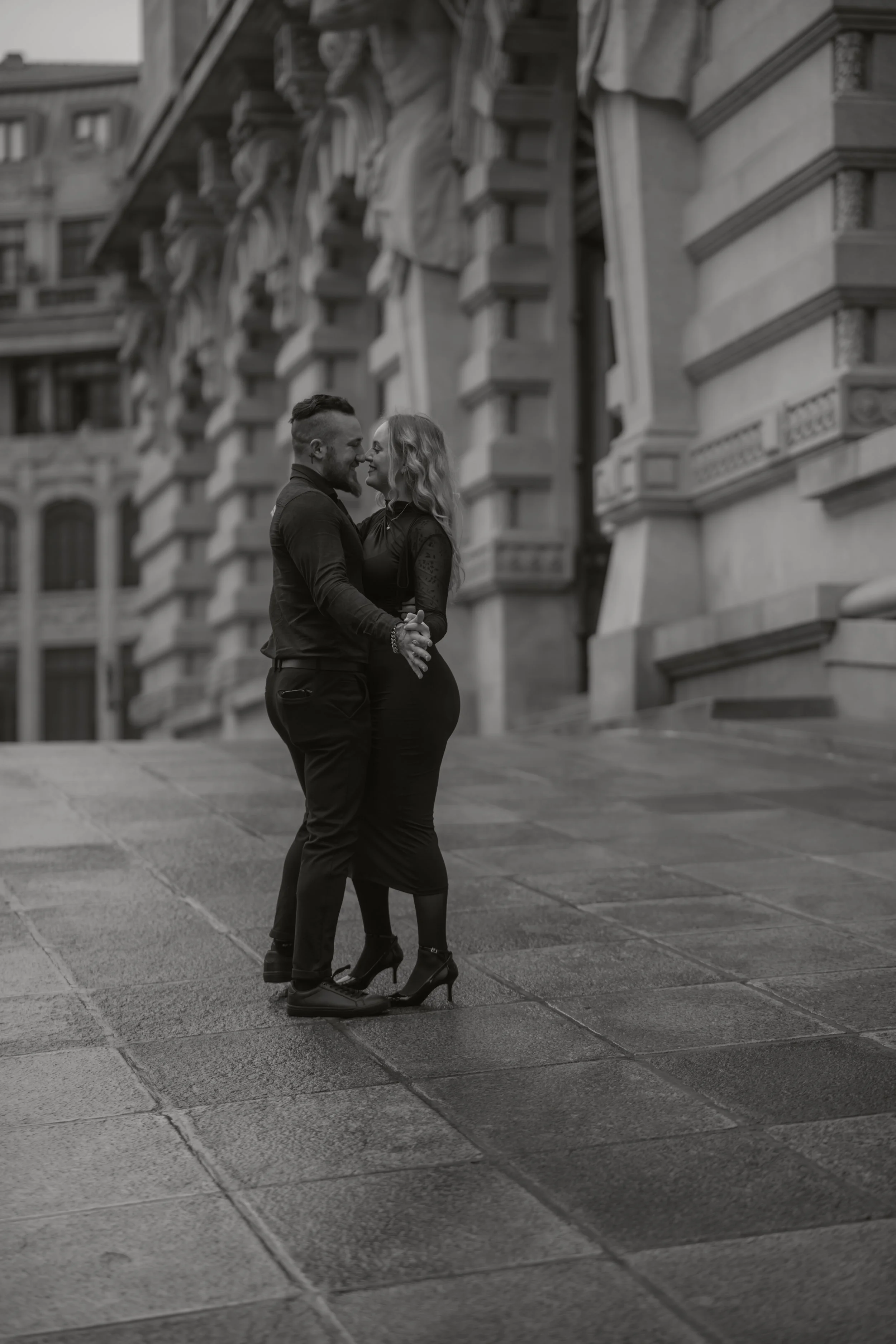 Ein Paar tanzt auf einer städtischen Straße vor einem historischen Gebäude.