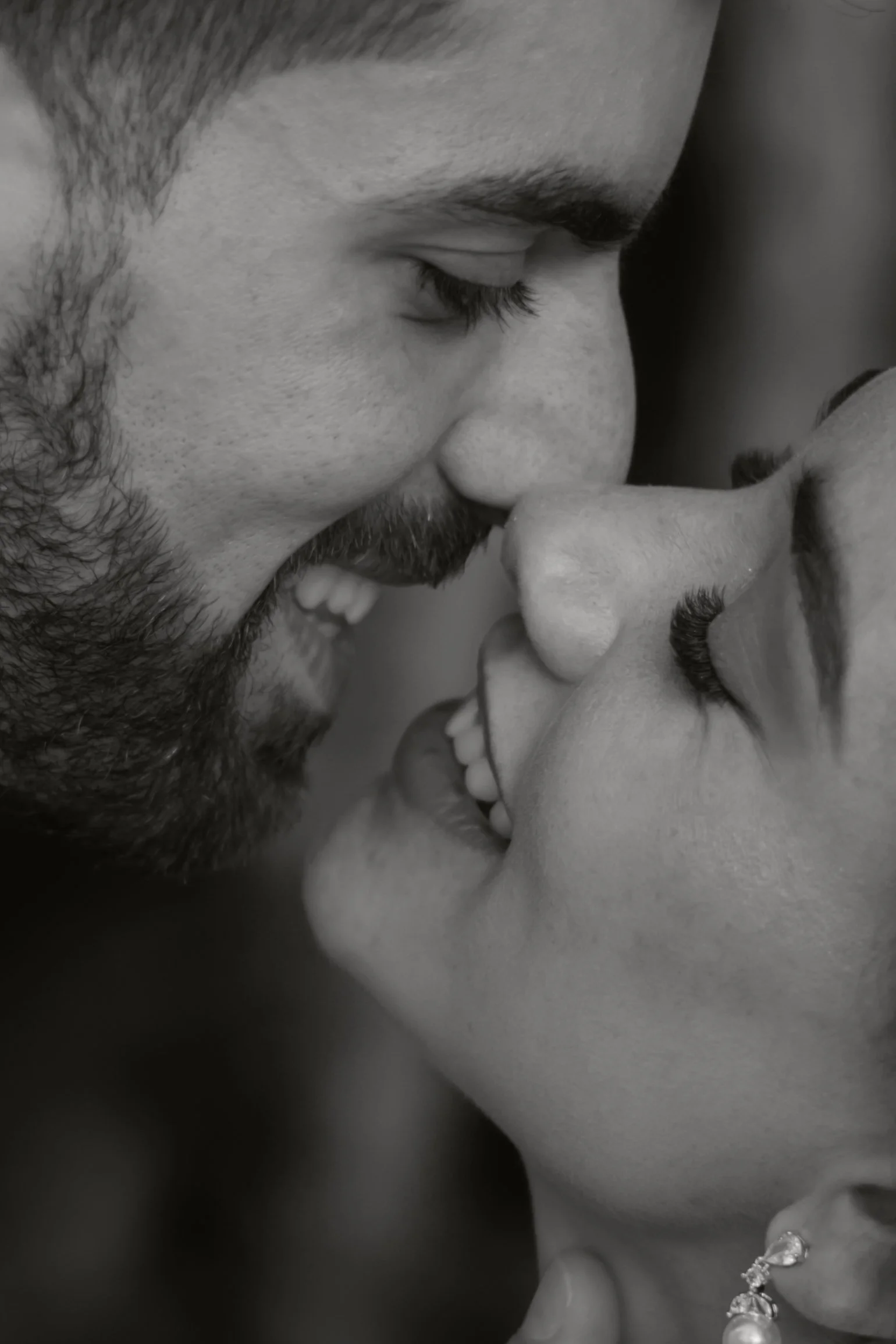 Ein glückliches Paar, das sich fast mit der Nase berührt, lächelt und sich liebevoll anschaut.