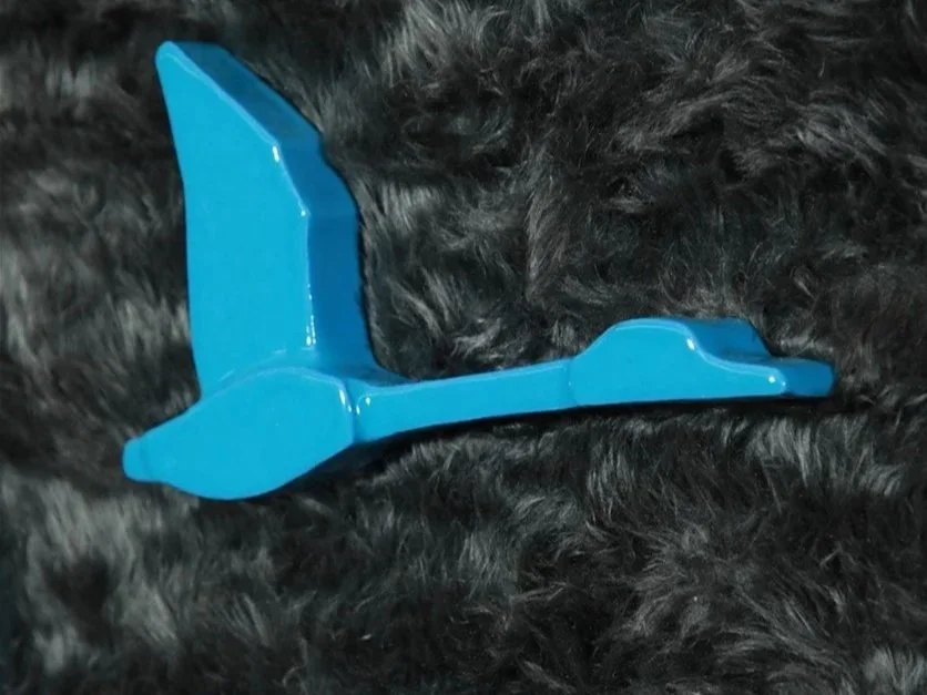 A blue ceramic flying swan on soft black furry fabric.