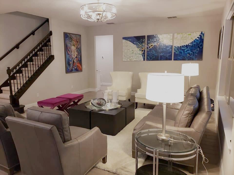 Living Room in the Heart of the Home with a High End Coffee Table, Leather Sofa and Matching Chairs and Pink Benches with White Leather Wing Chairs