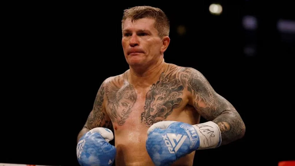 Ricky ‘The Hitman’ Hatton wearing blue boxing gloves, standing in a boxing ring.