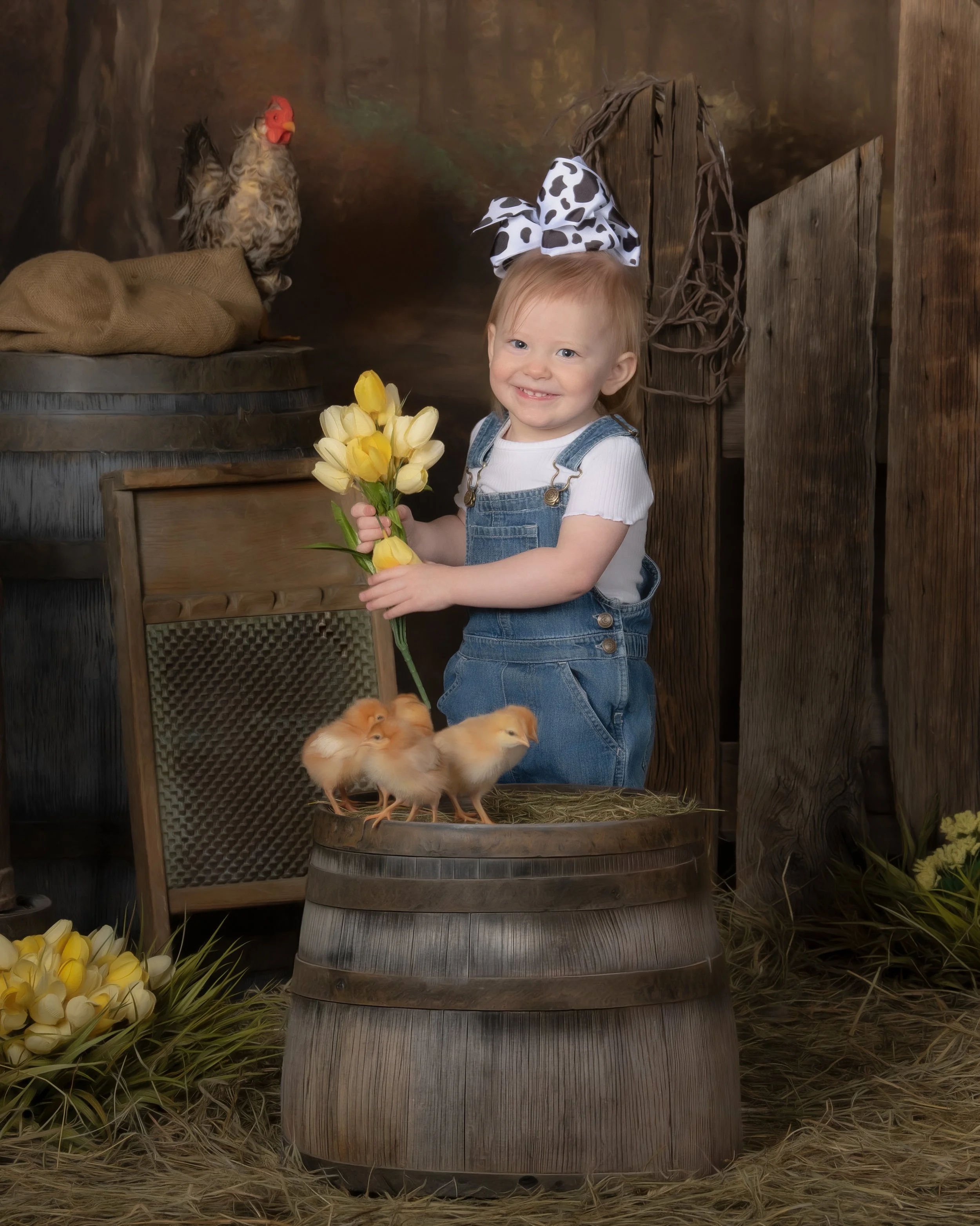 A young girl with a big polka dot bow in her hair, holding a bouquet of yellow tulips, standing beside a barrel with baby chicks, in front of a rustic farm backdrop with a chicken perched on a barrel.
