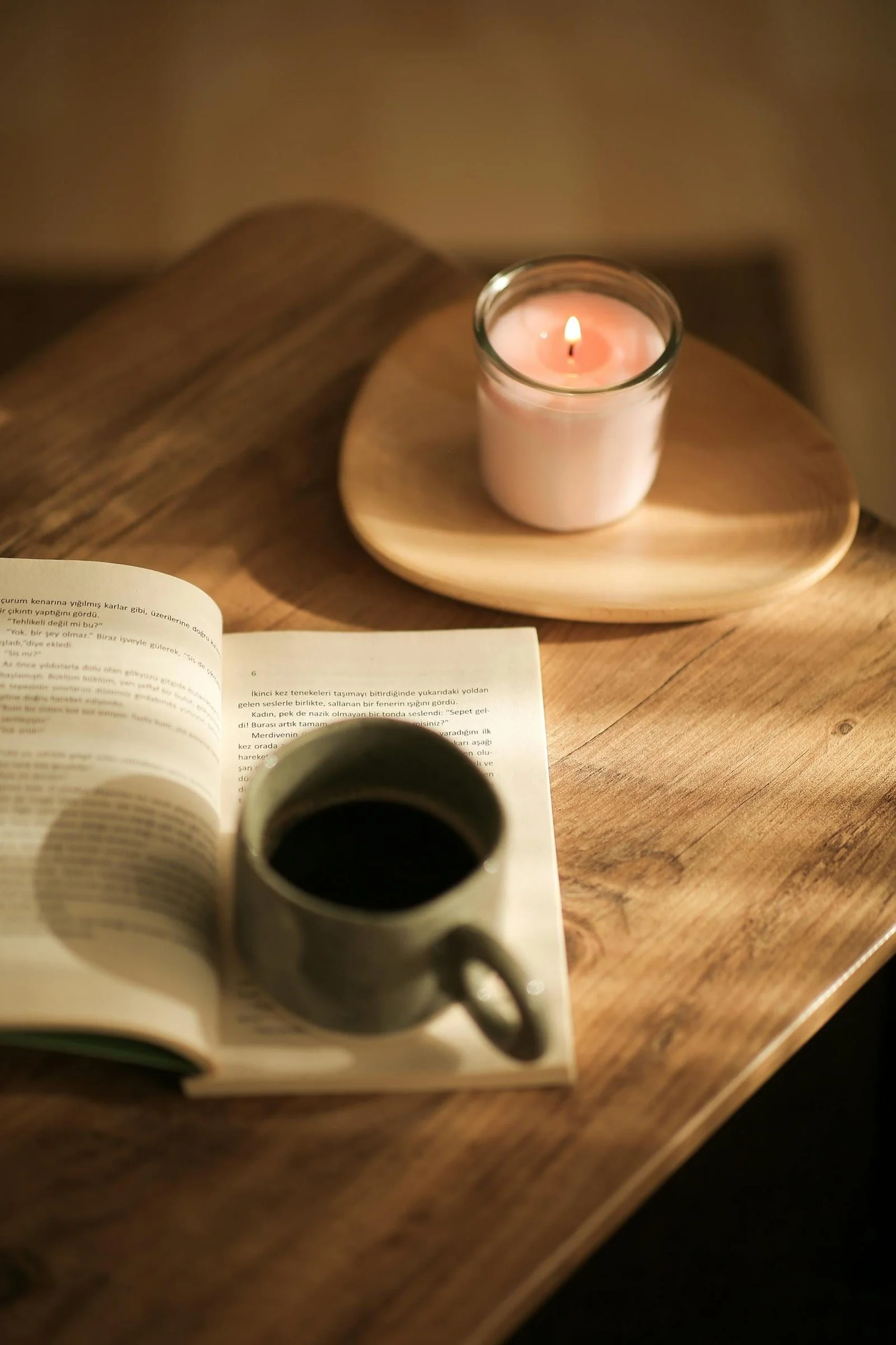 Open book beside a coffee mug on a wooden table, creating a calm, reflective atmosphere.