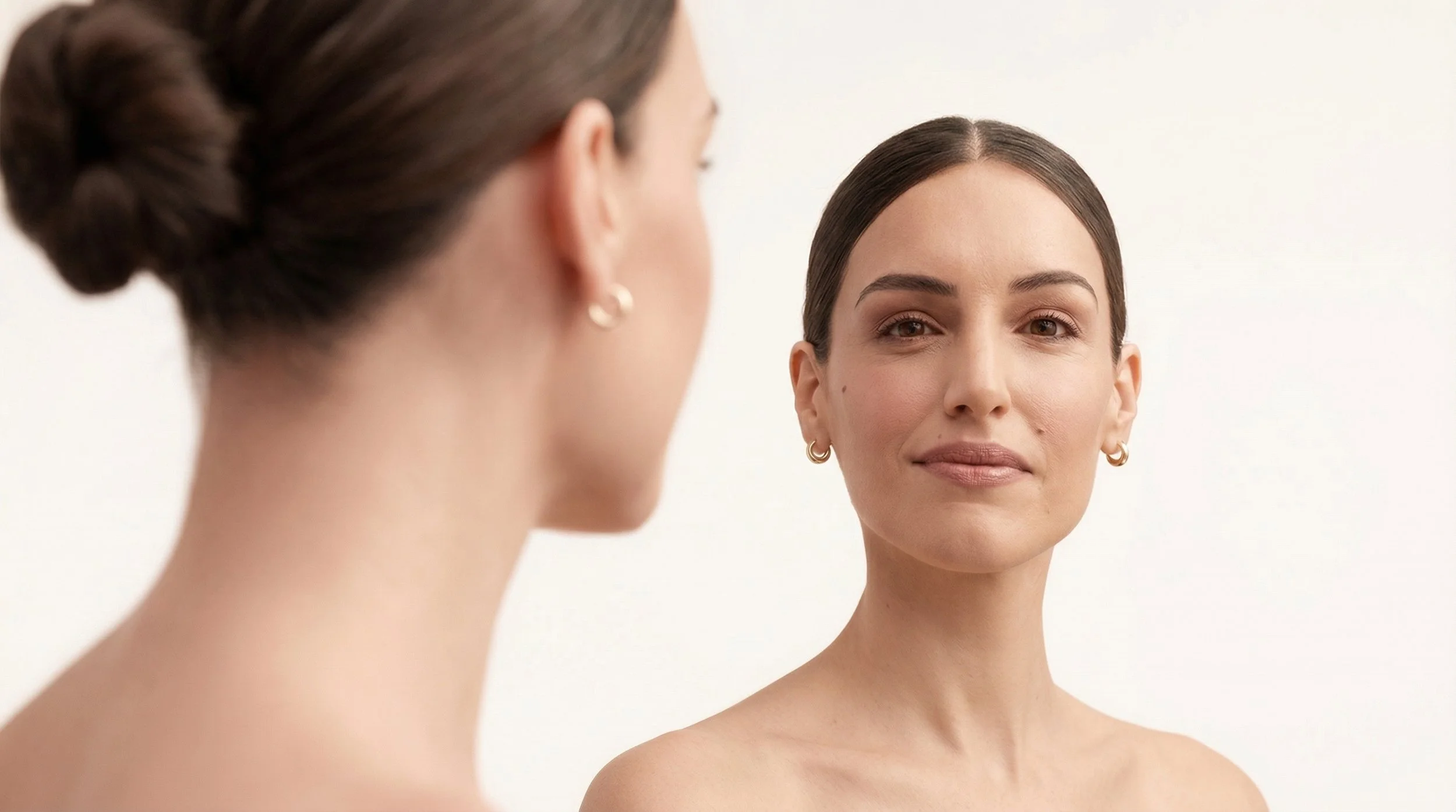 Deux femmes se regardent, l'une de face et l'autre de profil, contre un fond blanc, avec peu de maquillage.