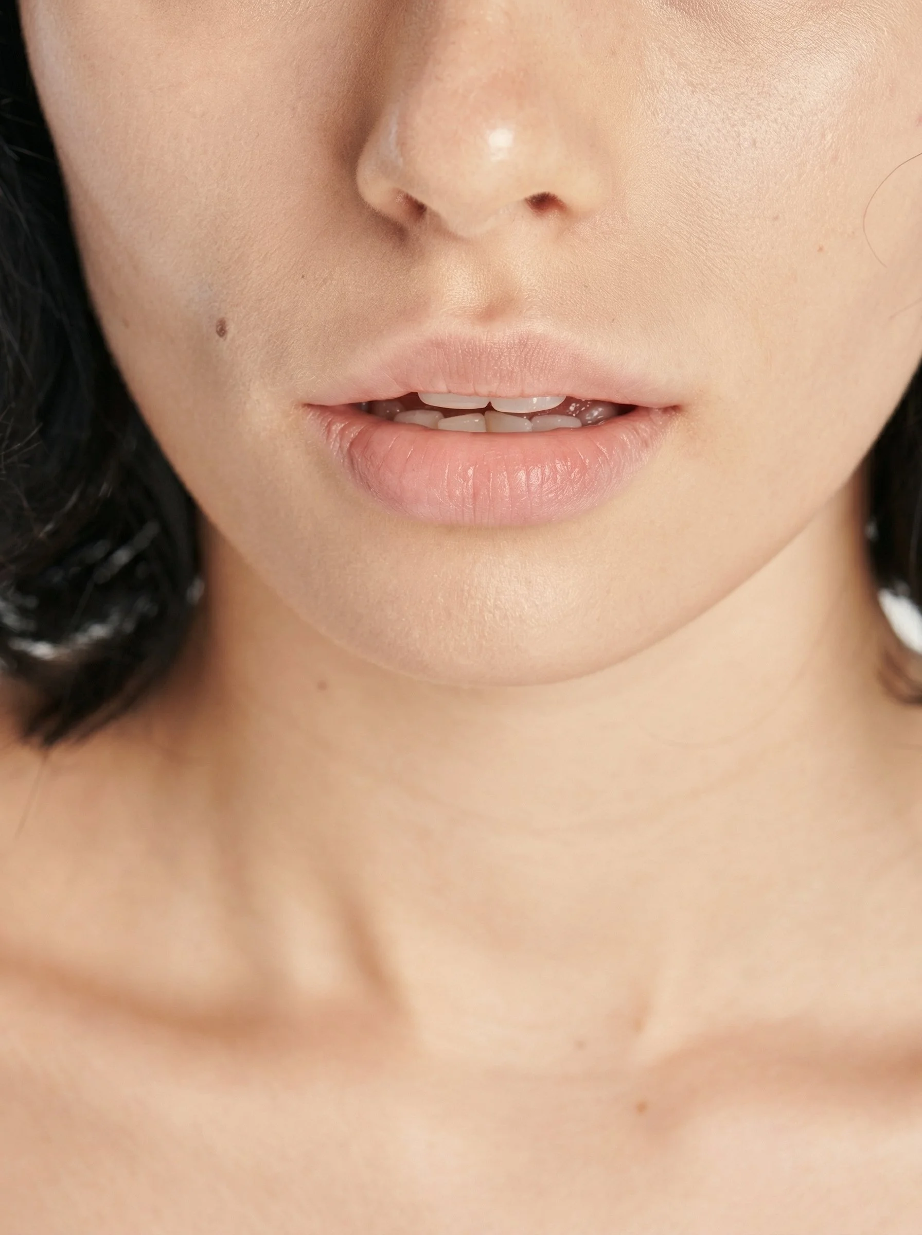 Zoom sur le visage d'une femme montrant ses lèvres légèrement ouvertes et ses dents.