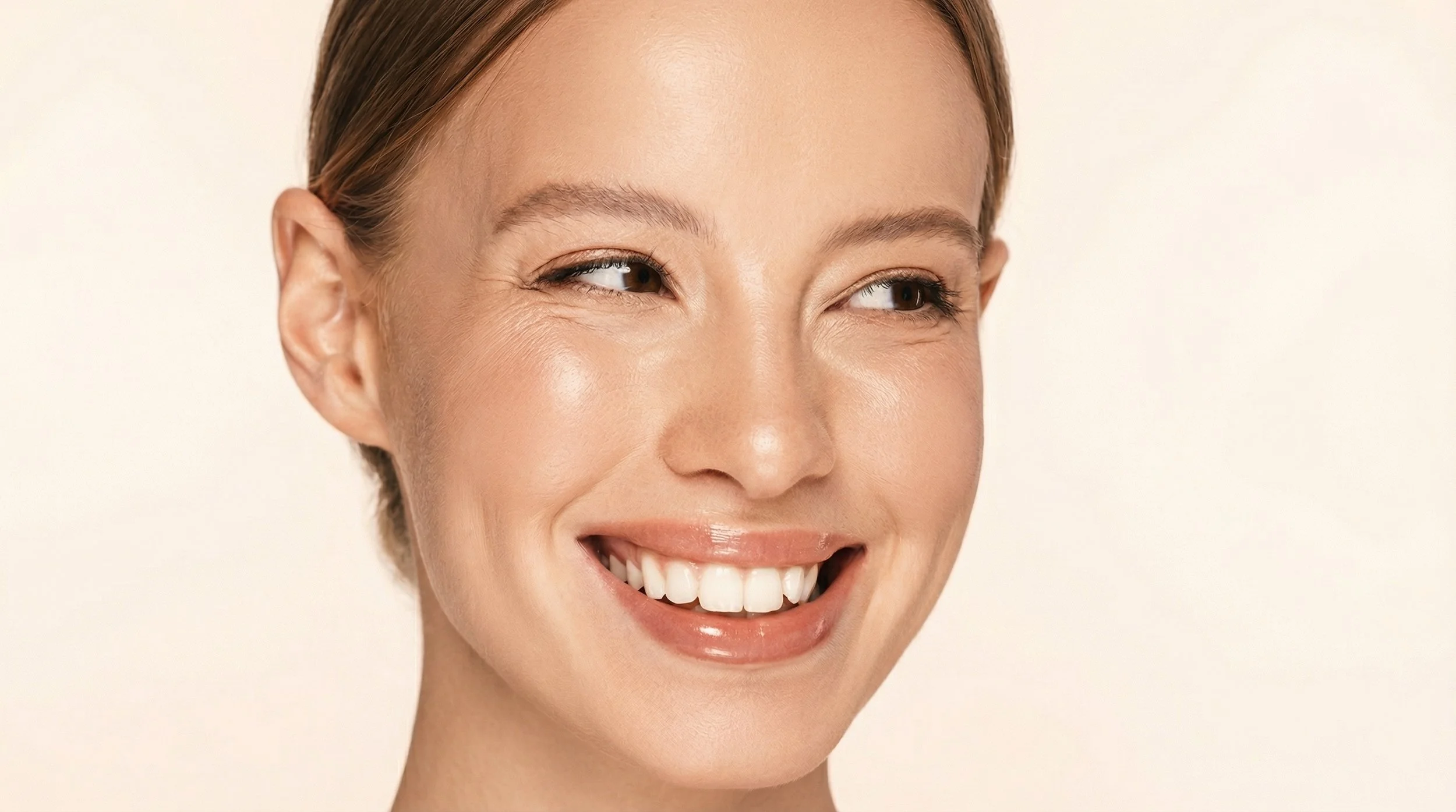 Femme souriante avec une peau claire, cheveux bruns, maquillage naturel.