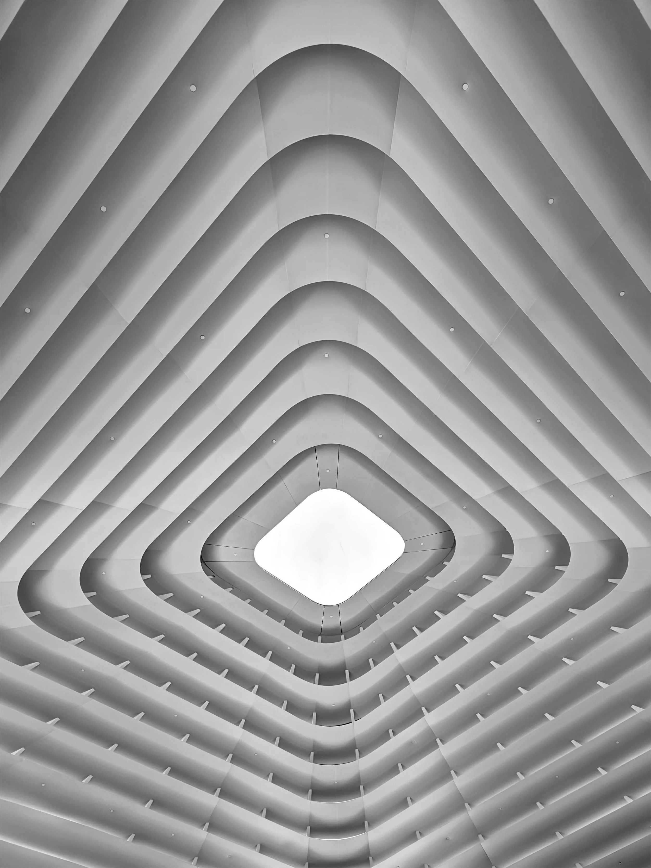 alt="Le Thai & Co modern multi-story building with a square-shaped open center, showing curved floors and a bright sky at the top"