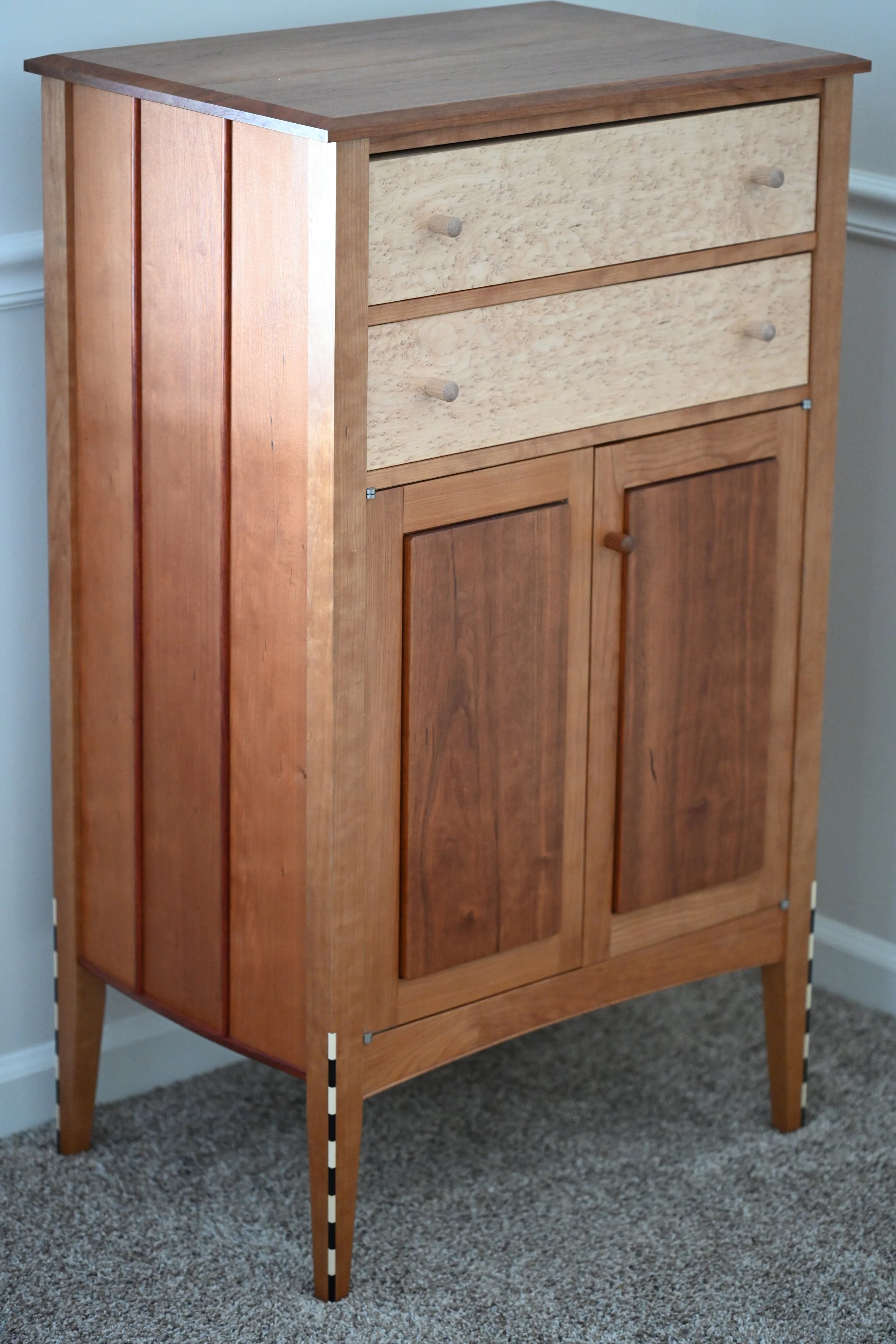 Uniquely designed Wooden dresser made from cherry and birdseye maple. Contrasting ebony and holly inlays on the front legs