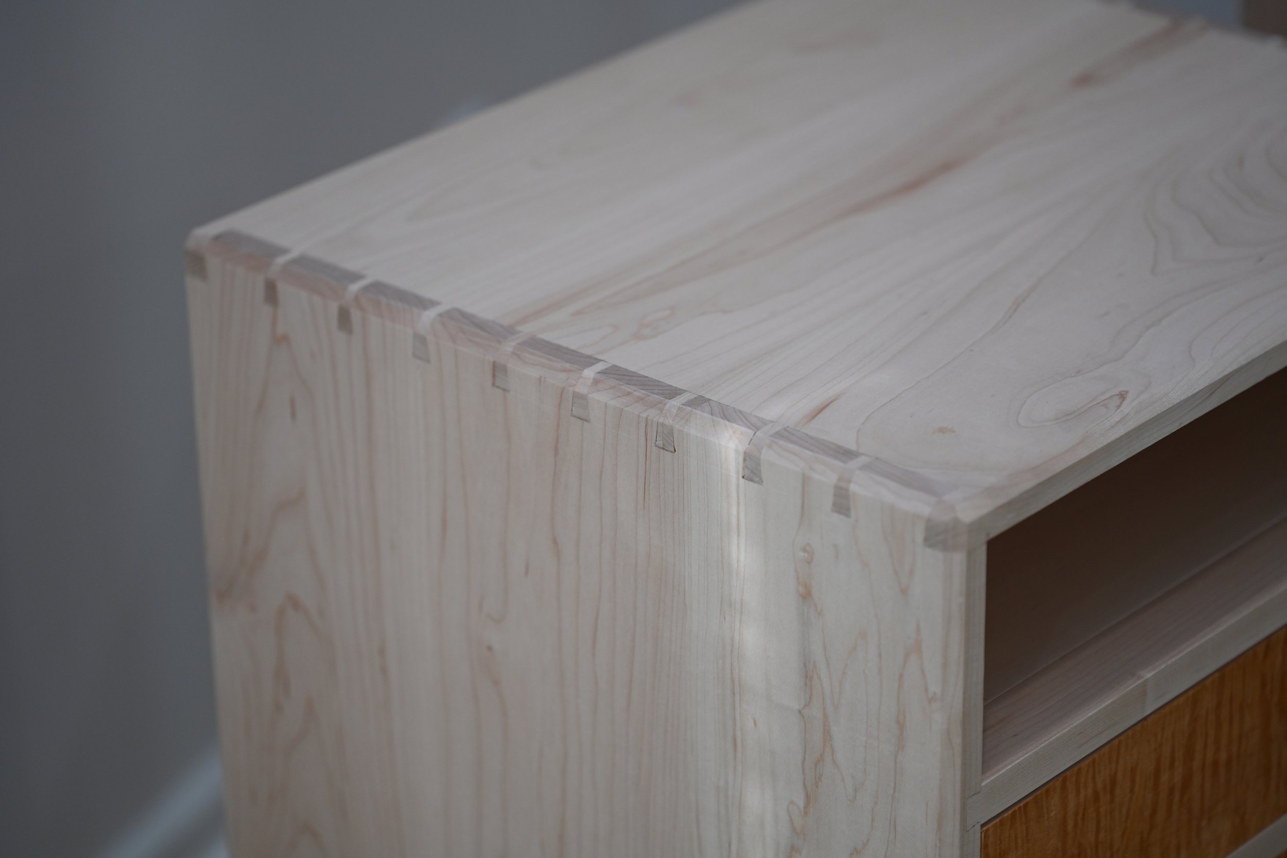 Close-up of a maple nightstand with through, hand cut dovetails.