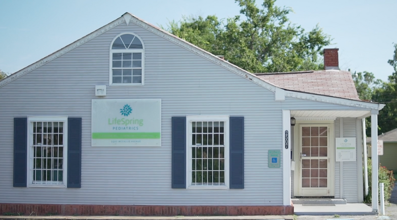 Exterior of LifeSpring Pediatrics clinic with blue shutters, a sign, and accessible entrance