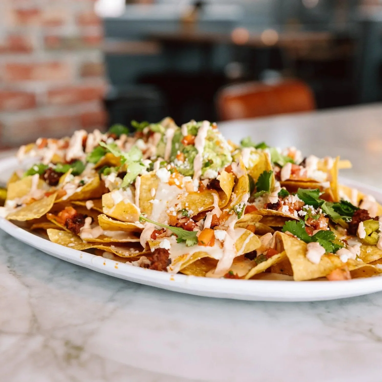 Close-up of loaded nachos on a bar table at The goat.